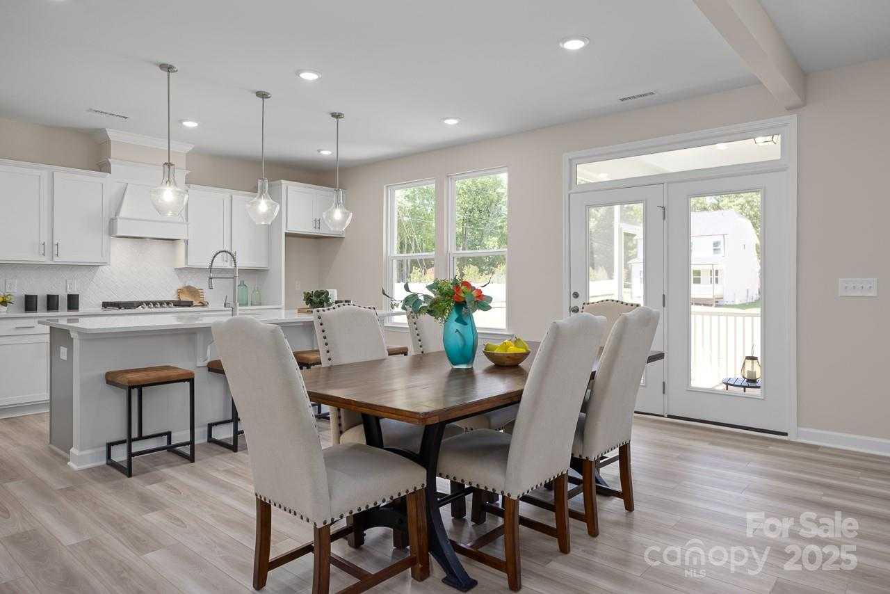 Spacious open kitchen with white cabinets, island sink, and dining table overlooking backyard via French doors in Davidson Homes The Chestnut F, Belmont NC