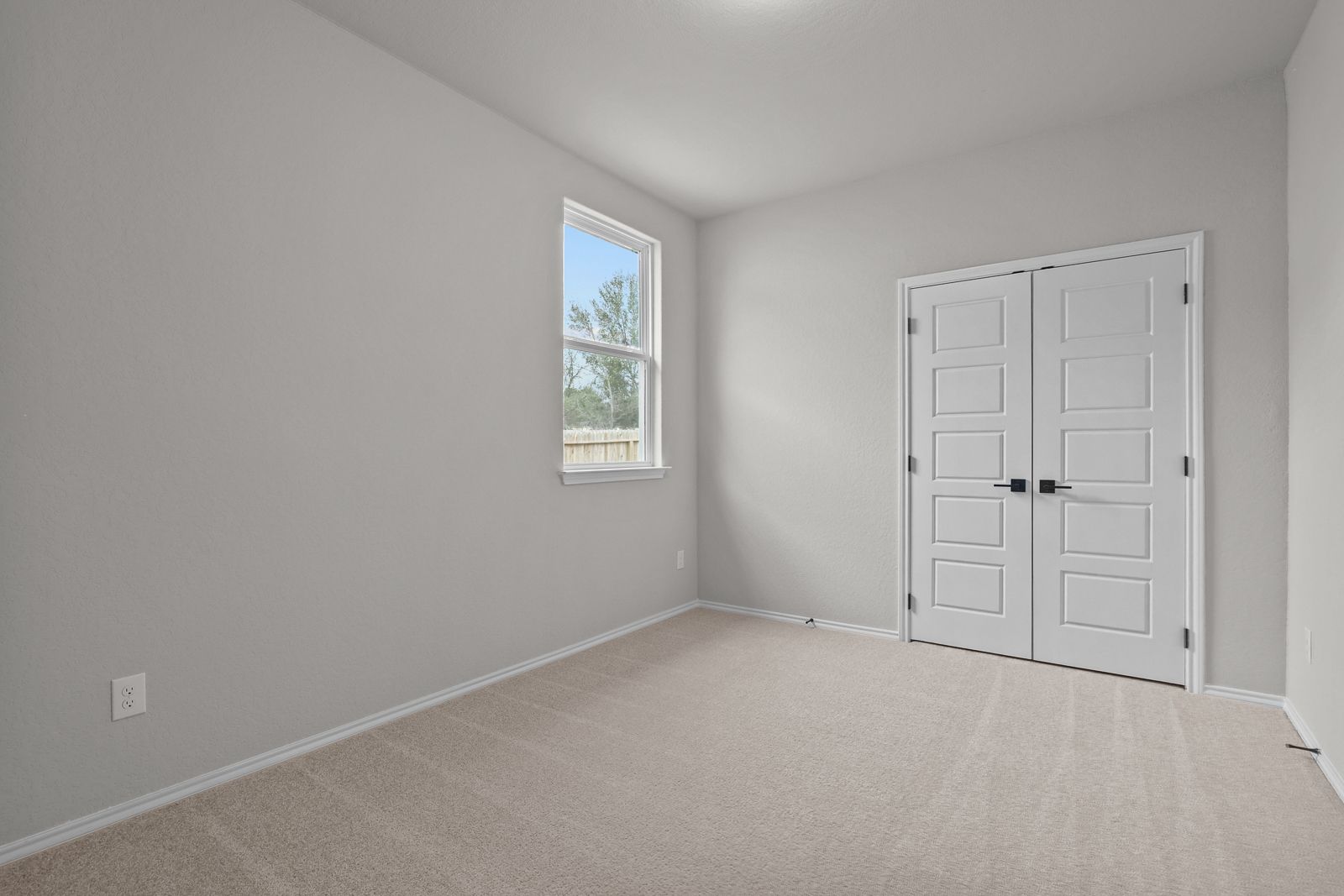 Bright bedroom in The Glenwood E by Davidson Homes featuring neutral carpet, soft wall tones, and double closet doors.