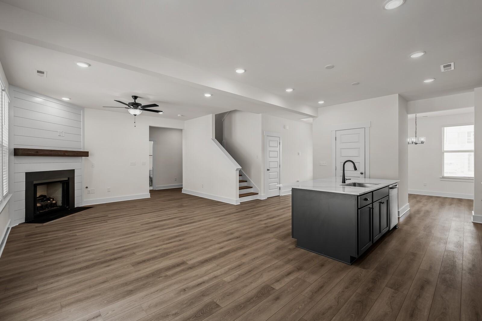 Open-concept living room with shiplap fireplace and kitchen island in The Willow floor plan at Woods Crossing, Gallatin.