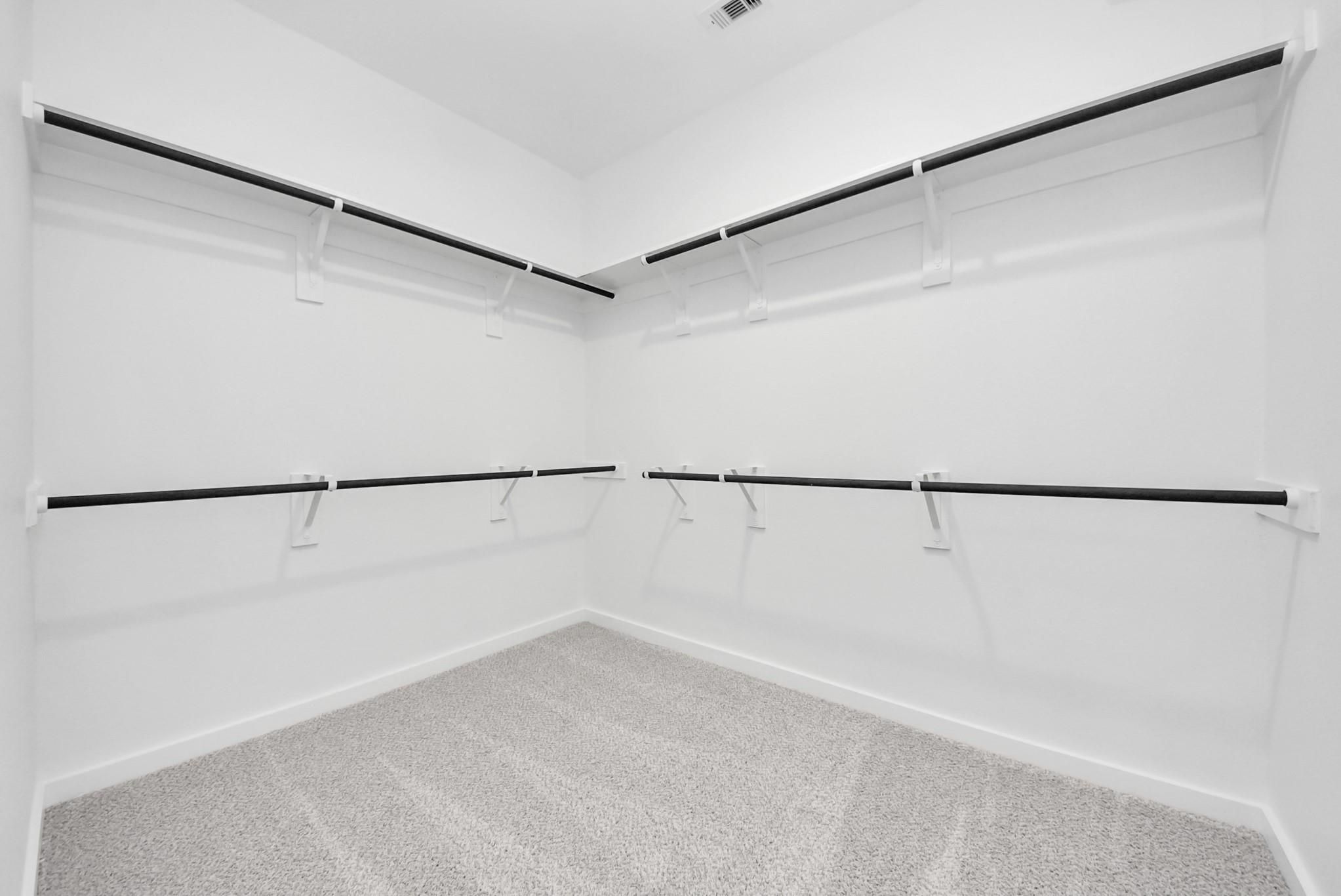 Spacious walk-in closet with double-tier shelving in The Verano B floor plan by Davidson Homes in Sunterra, Katy, Texas.