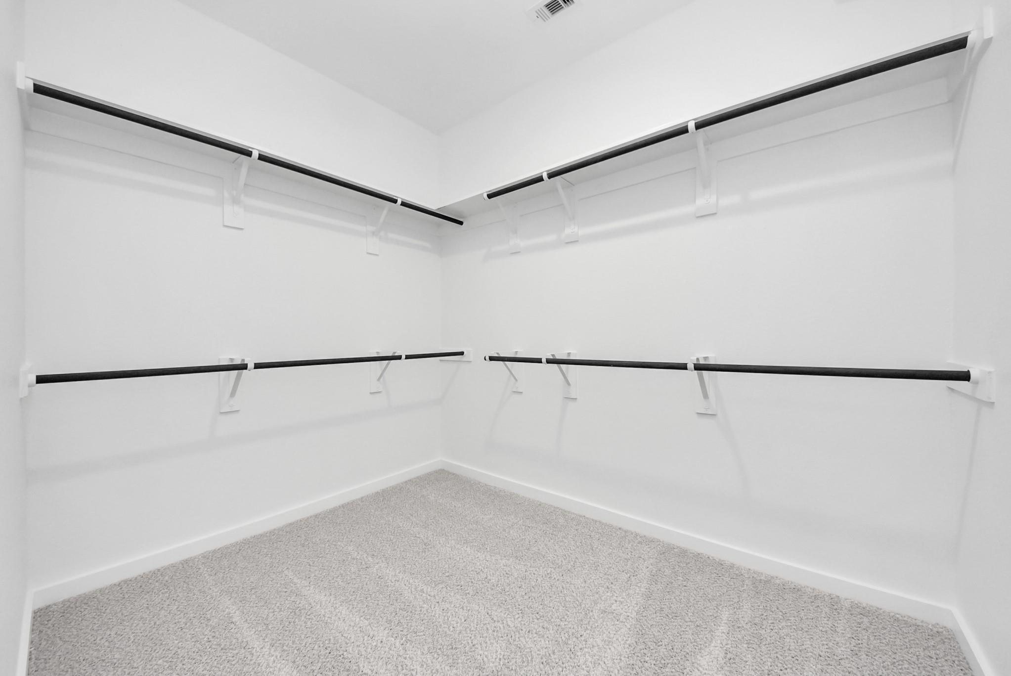 Spacious walk-in closet with double-tier shelving in The Verano B floor plan by Davidson Homes in Sunterra, Katy, Texas.