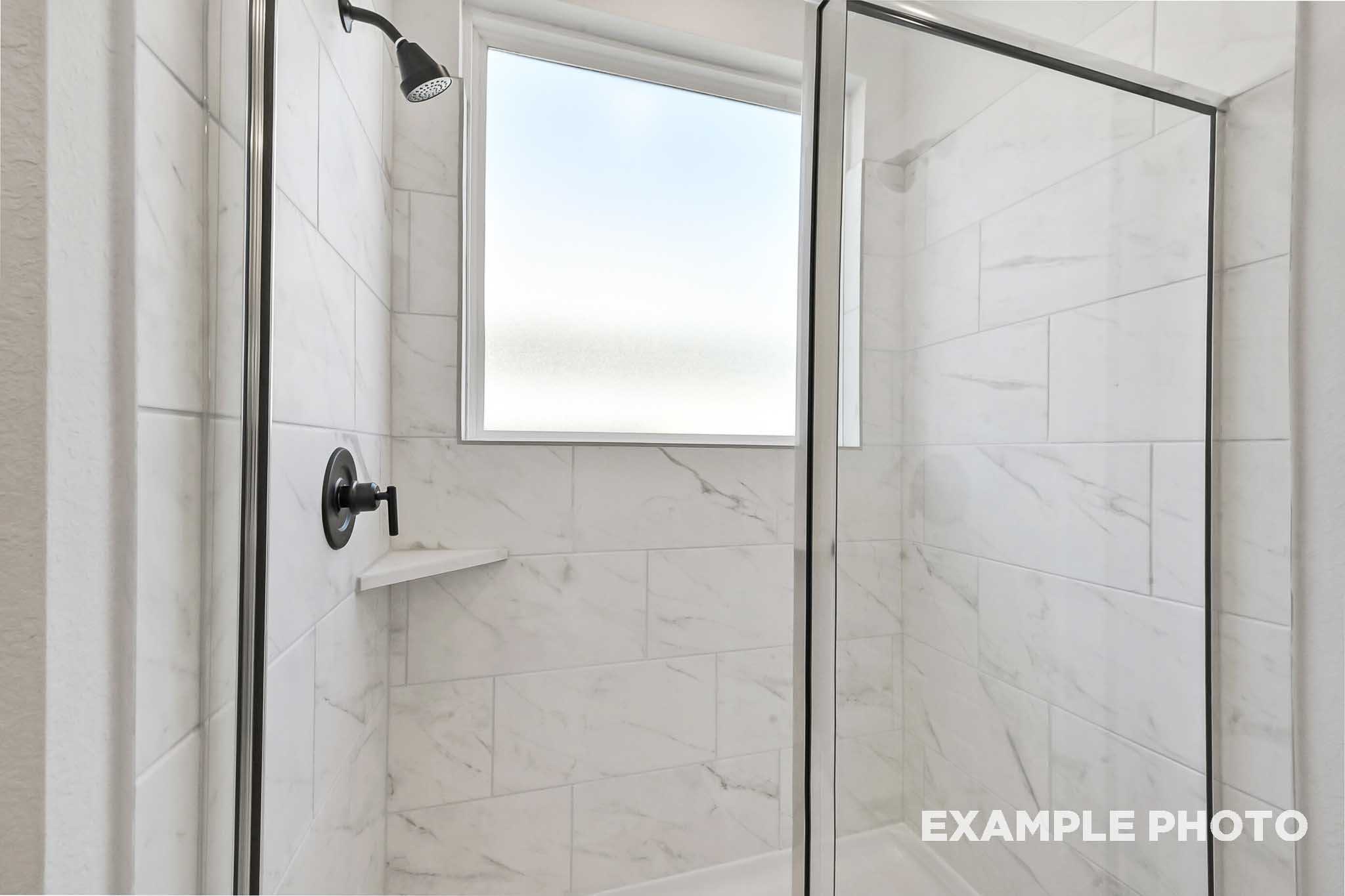 Walk-in shower in The Sequoia master bathroom featuring frameless glass enclosure, white subway tiles, and rainfall showerhead