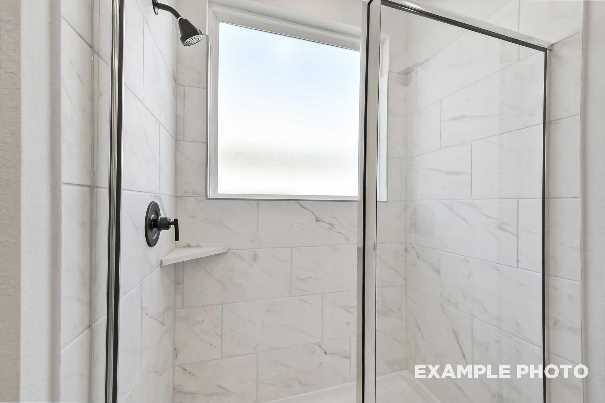 Walk-in shower in The Sequoia master bathroom featuring frameless glass enclosure, white subway tiles, and rainfall showerhead