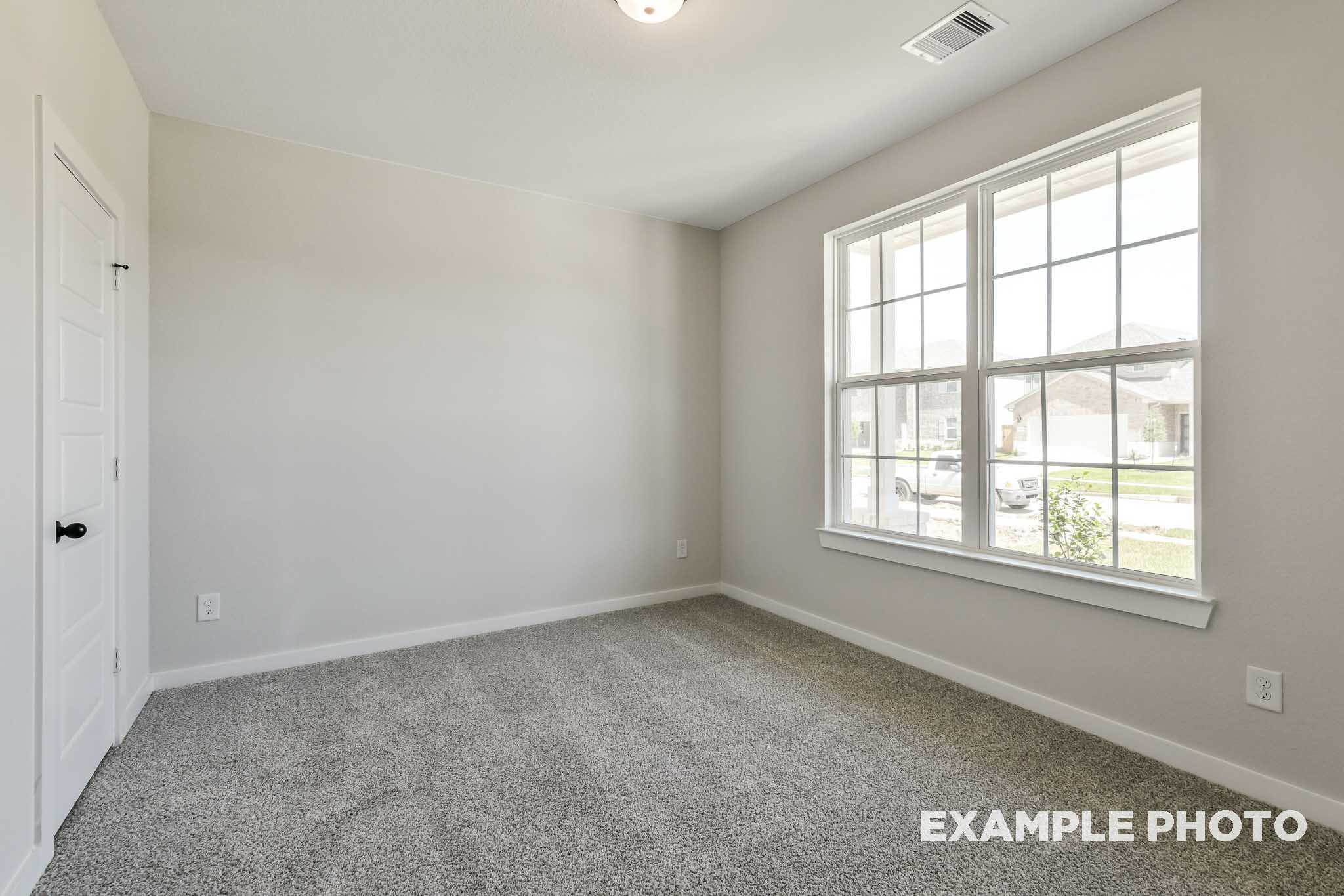 Spacious secondary bedroom in The Daphne G with large window, beige carpet, light gray walls, and neutral tones