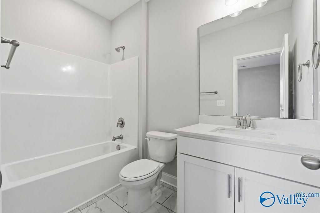 Bright white bathroom with tub-shower combo, single vanity sink, and toilet in Davidson Homes The Harrison, Hartselle AL