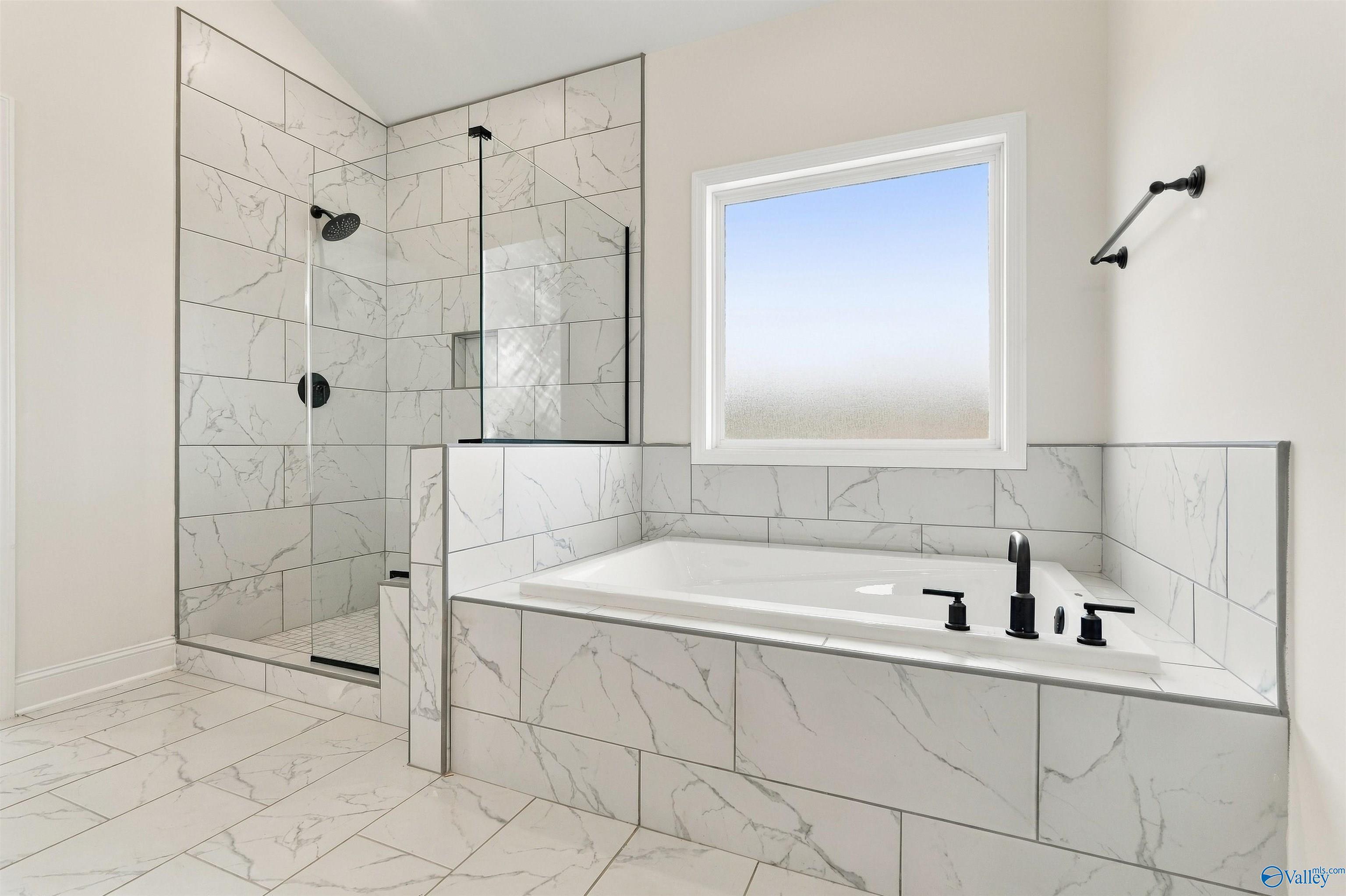 Marble-tiled master bathroom with soaking tub, glass walk-in shower, and matte black fixtures in Davidson Homes' Valencia, Huntsville