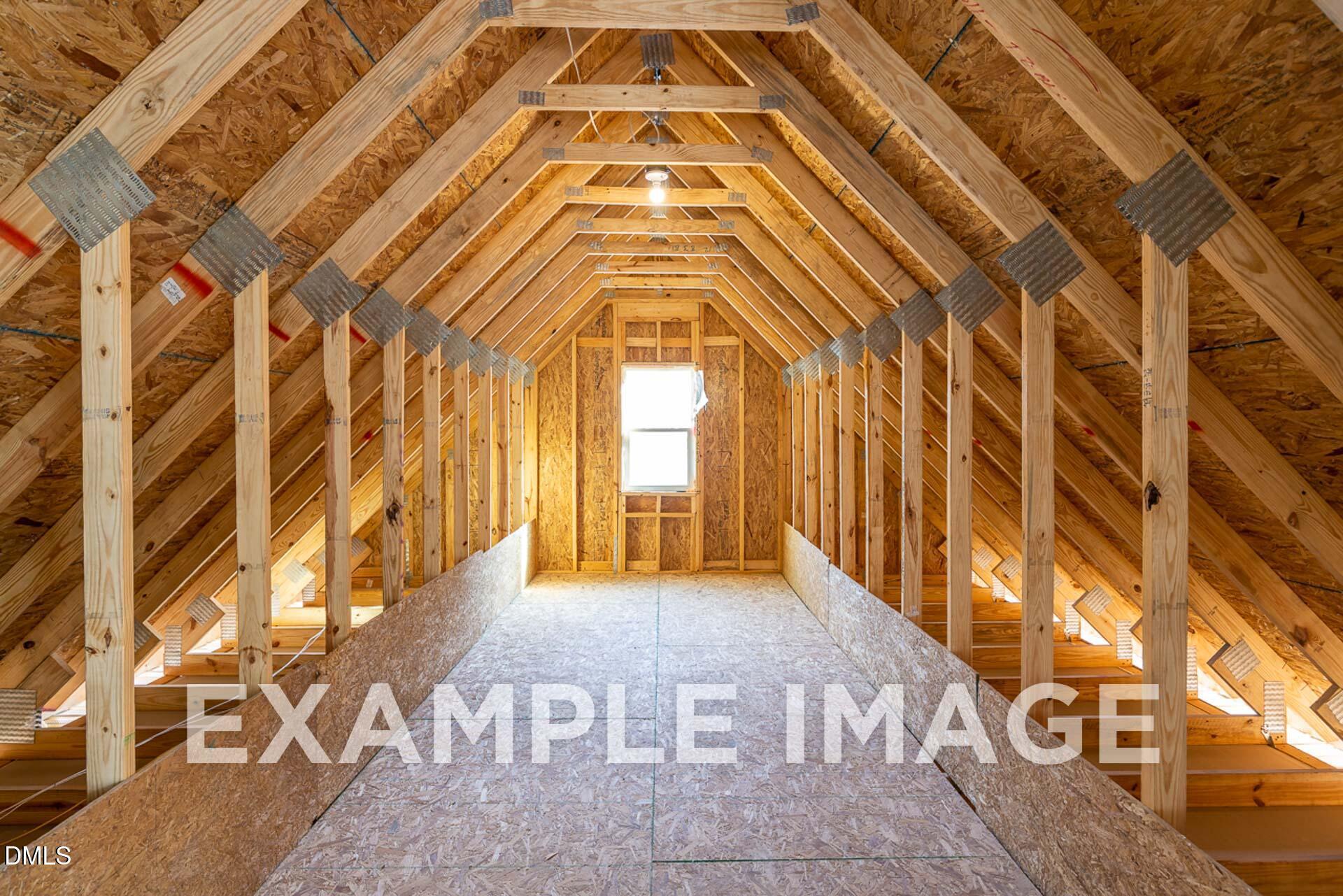 Exposed wooden trusses and beams in attic framing of 2-story The Ash B home by Davidson Homes, Zebulon, NC