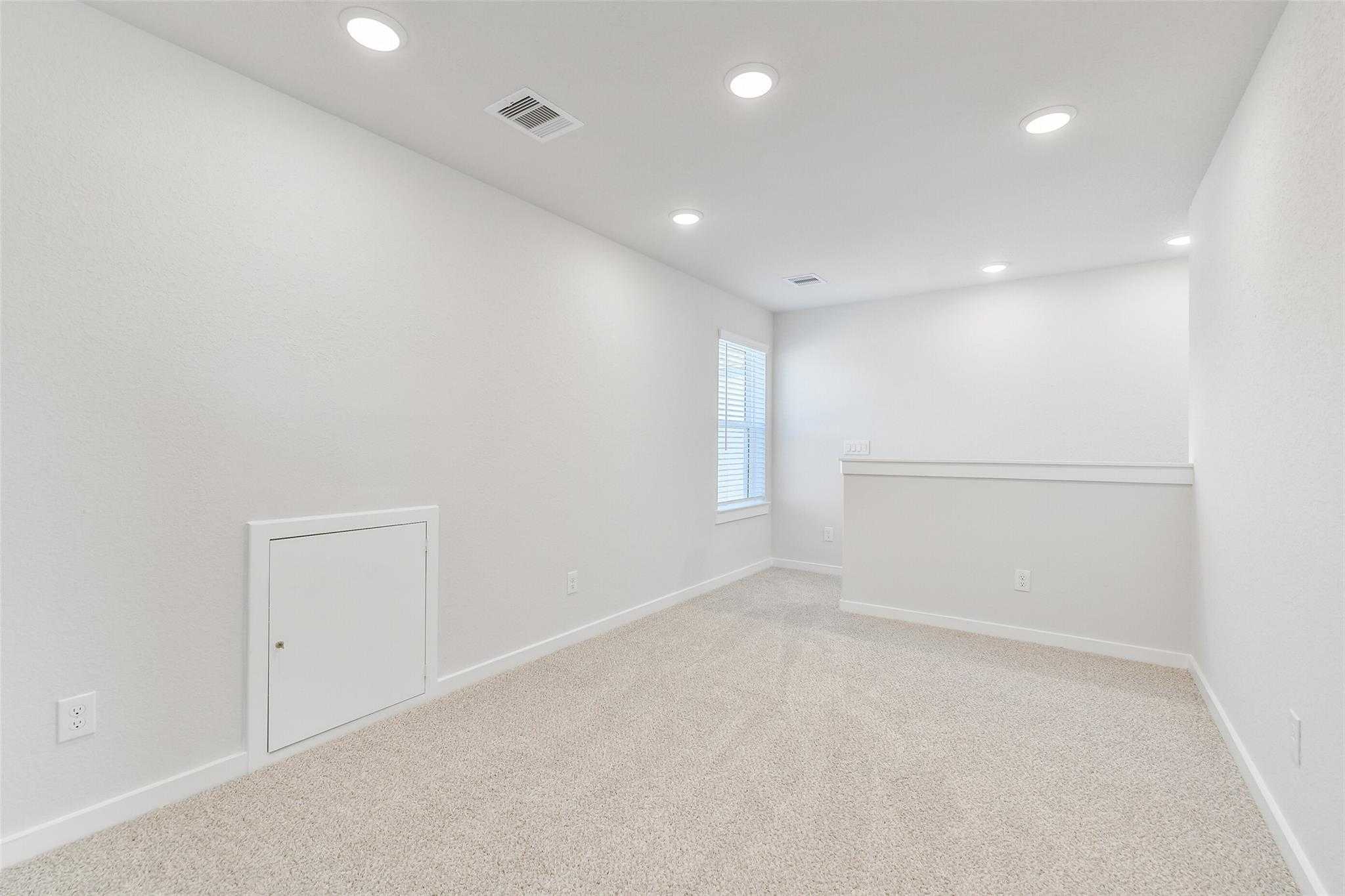 Bright upstairs loft with beige carpet, white walls, recessed lights, and window in Davidson Homes The Blanco E, Magnolia Texas