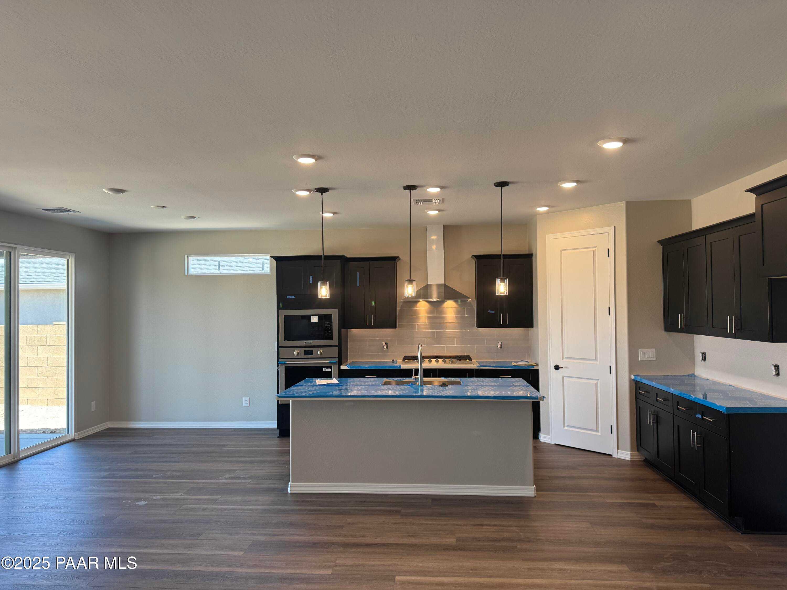 Modern open-concept kitchen featuring dark cabinets, large island, stainless appliances in Davidson Homes Durango II A, Prescott AZ