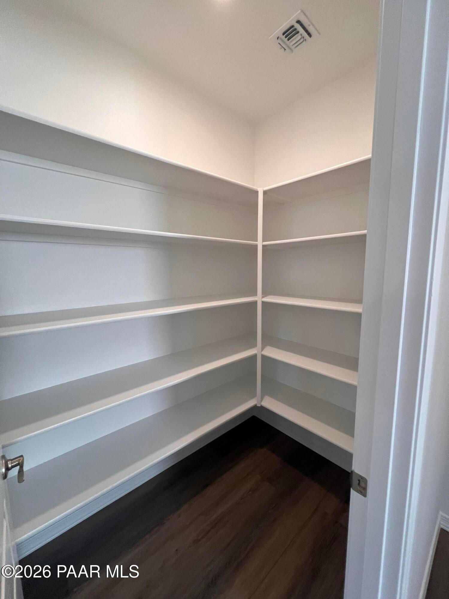 Spacious walk-in pantry with white corner shelving and hardwood floors in Davidson Homes The Summit A, Prescott, Arizona