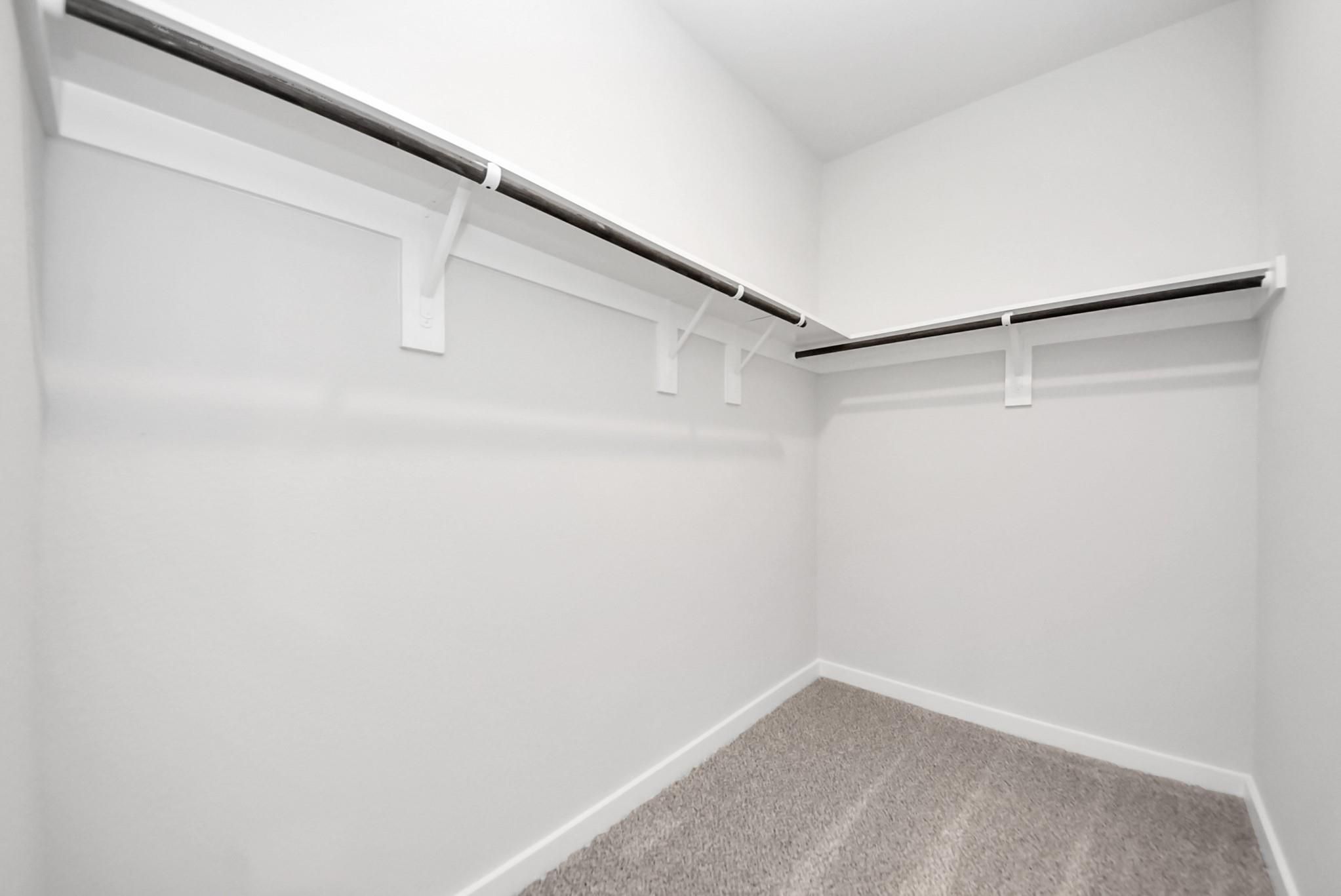 Walk-in closet with shelving and rods in The Sabine E floor plan by Davidson Homes in Windmill Estates, Magnolia, Texas.
