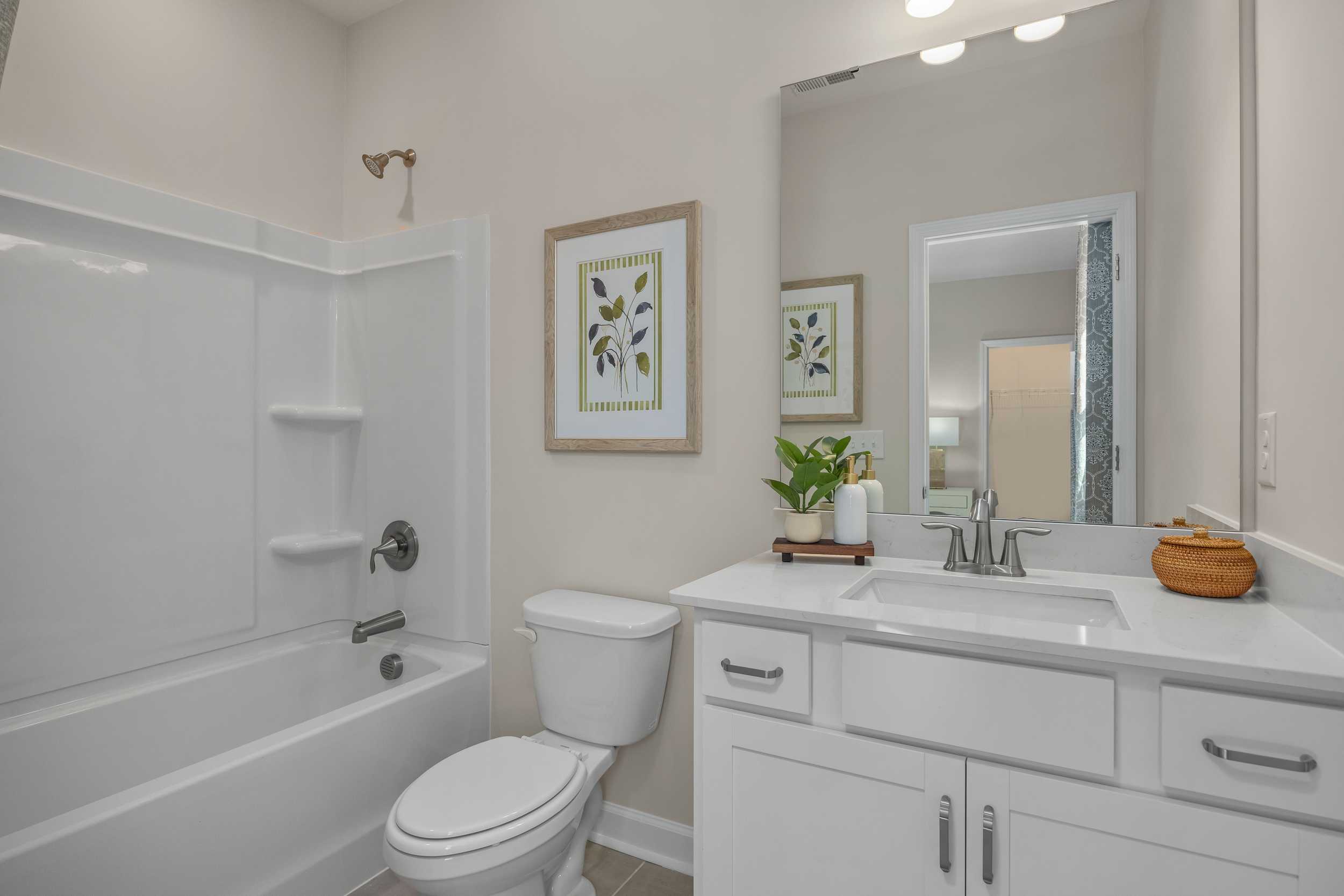Spacious master bathroom in The Hickory II E with white bathtub, vanity, mirror, and potted plants, Davidson Homes design