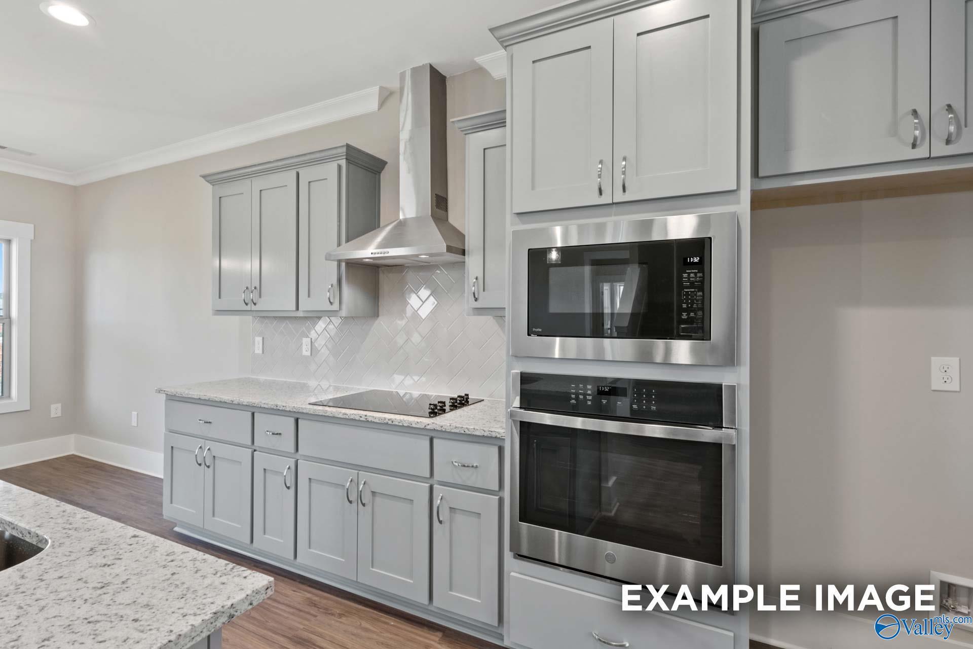 Modern kitchen featuring gray shaker cabinets, granite counters, stainless double oven and subway tile backsplash in Davidson Homes Shelby B, Huntsville AL