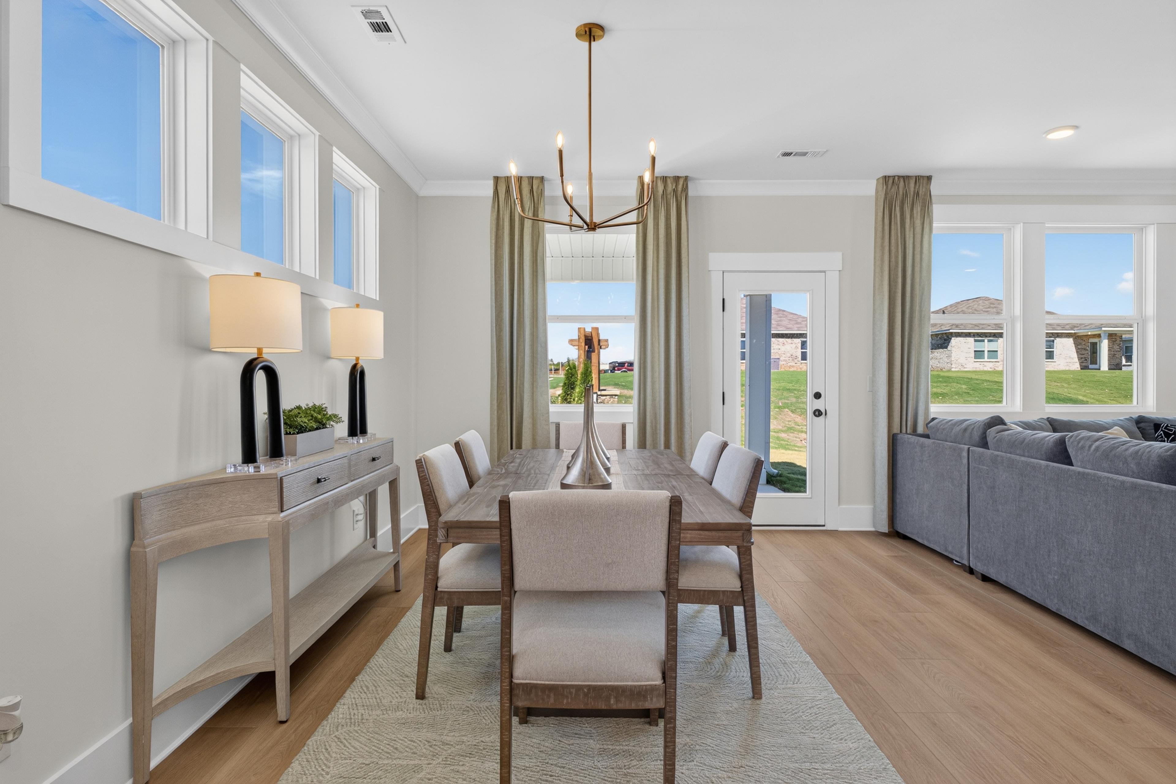 Bright dining room with wood table, gold chandelier, and hardwood floors at Evergreen Mill by Davidson Homes in Madison, Alabama