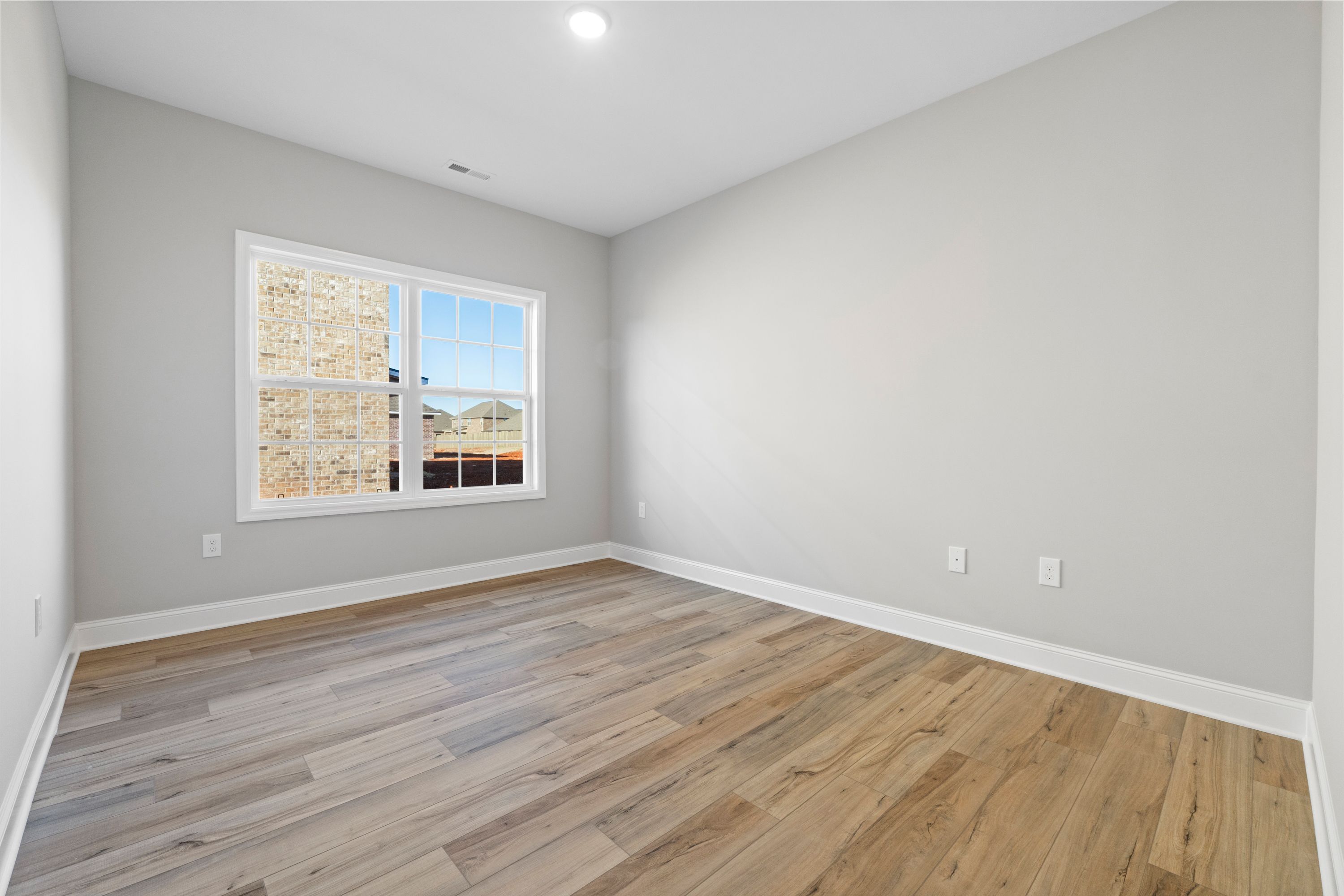 Spacious secondary bedroom in The Valencia with light gray walls, large window, hardwood floors, and recessed lighting