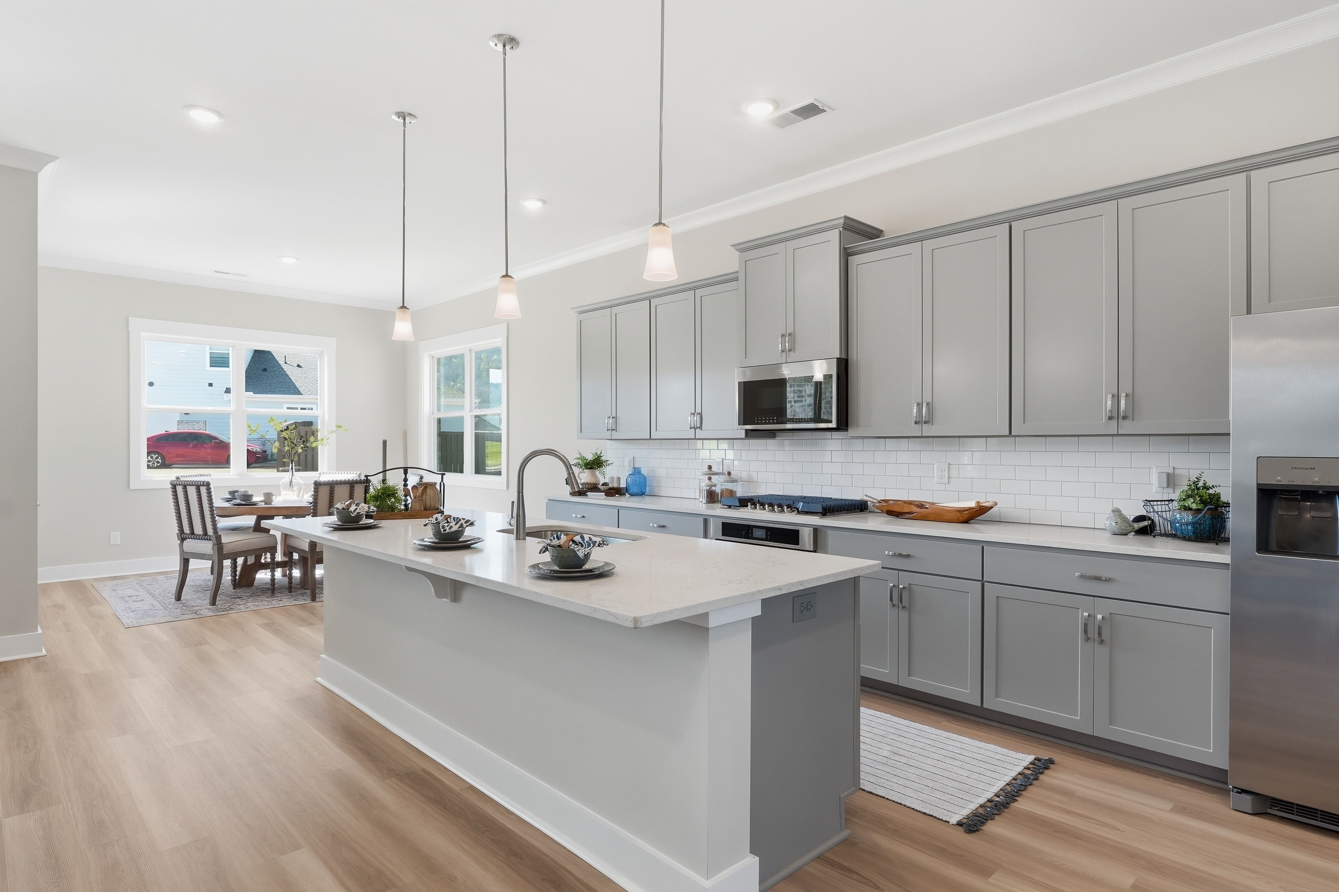 Spacious open-concept kitchen with gray cabinets, island, and dining area at The Meadows at Hampton Cove in Owens Cross Roads, AL