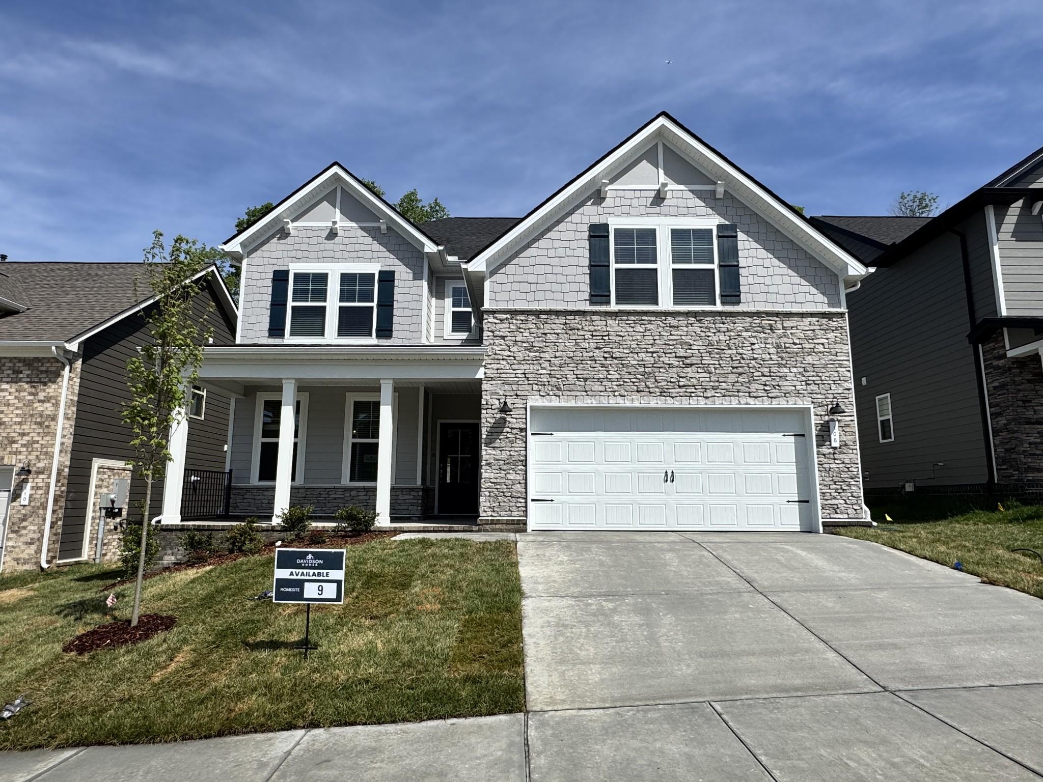 Modern two-story 5-bedroom home with gray siding, stone facade, front porch, and two-car garage in Woods Crossing, Gallatin, Tennessee by Davidson Homes The Willow