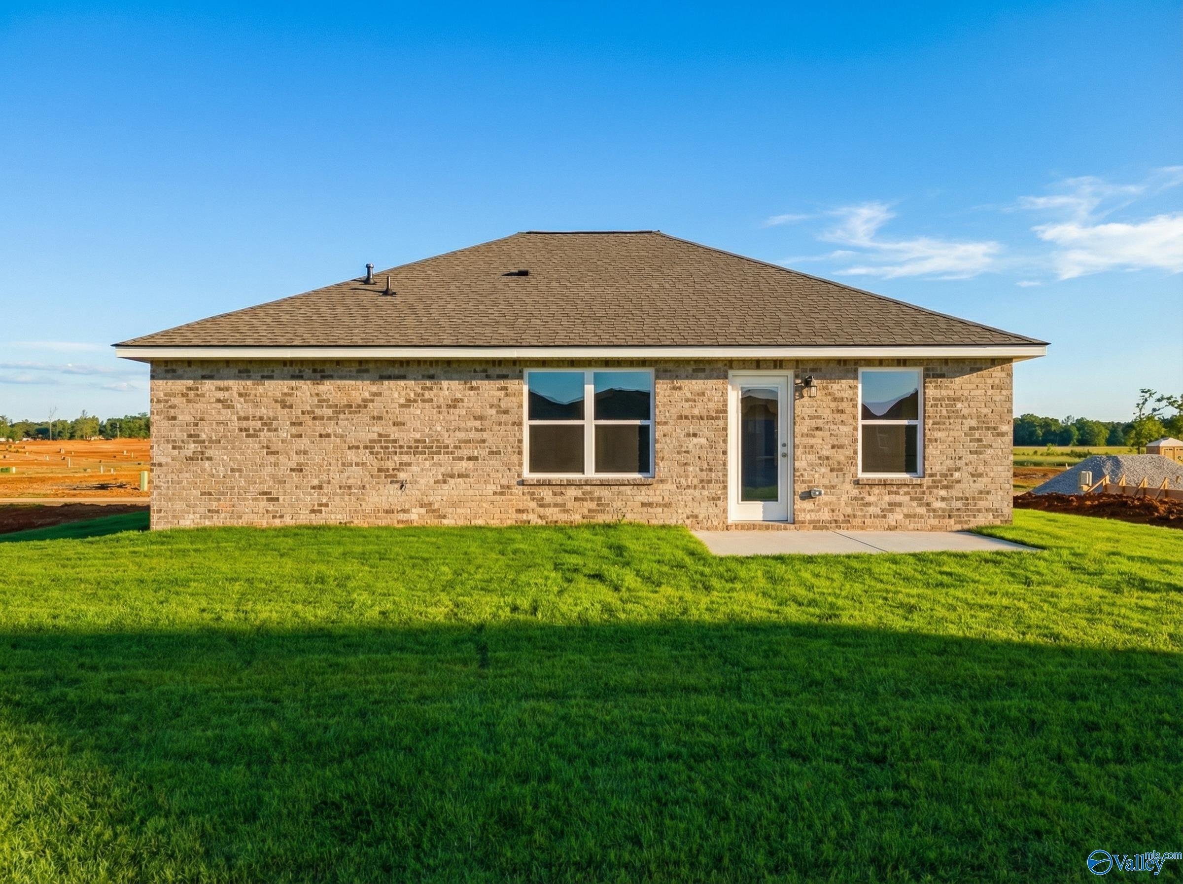 Rear view of The Butler 3-bedroom brick home by Davidson Homes in Heritage Lakes, New Market, Alabama, with covered patio and green lawn