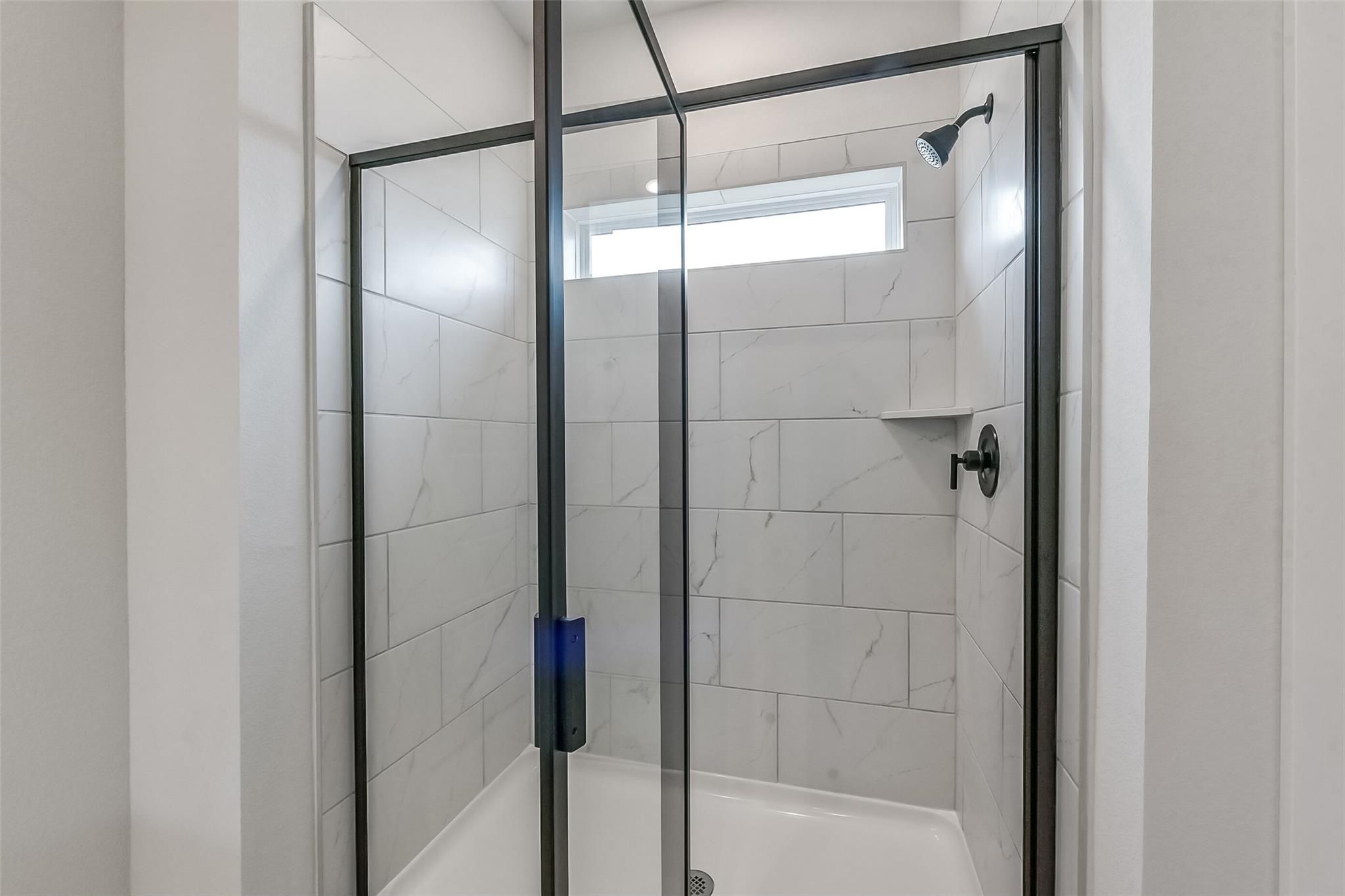 Modern frameless glass walk-in shower with white subway tiles, rainfall head, and clerestory window in master bath, The Everett C, Crosby TX