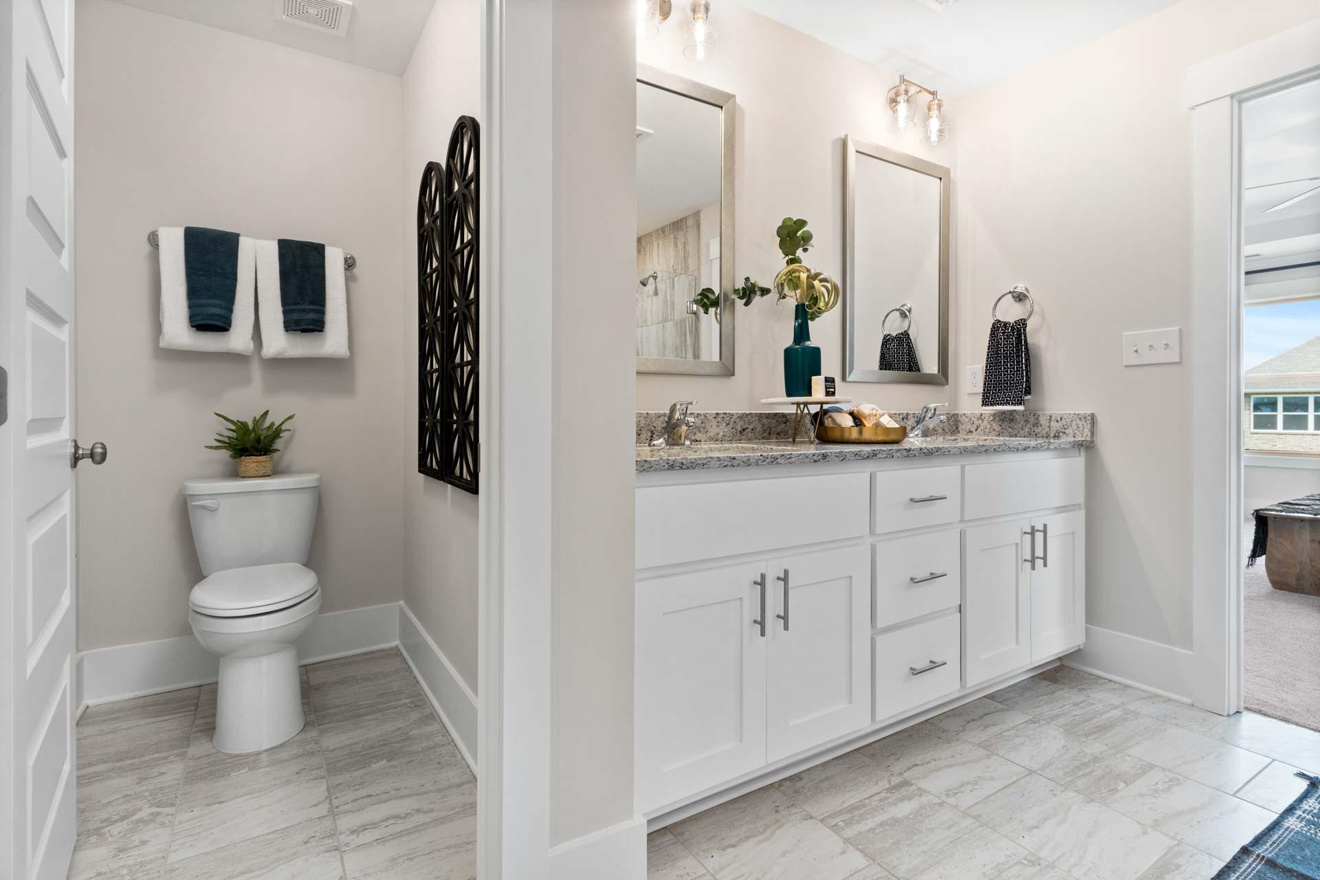 Spacious primary bathroom at Walker's Hill in Meridianville AL with double vanity, white shaker cabinets, and luxury tile flooring
