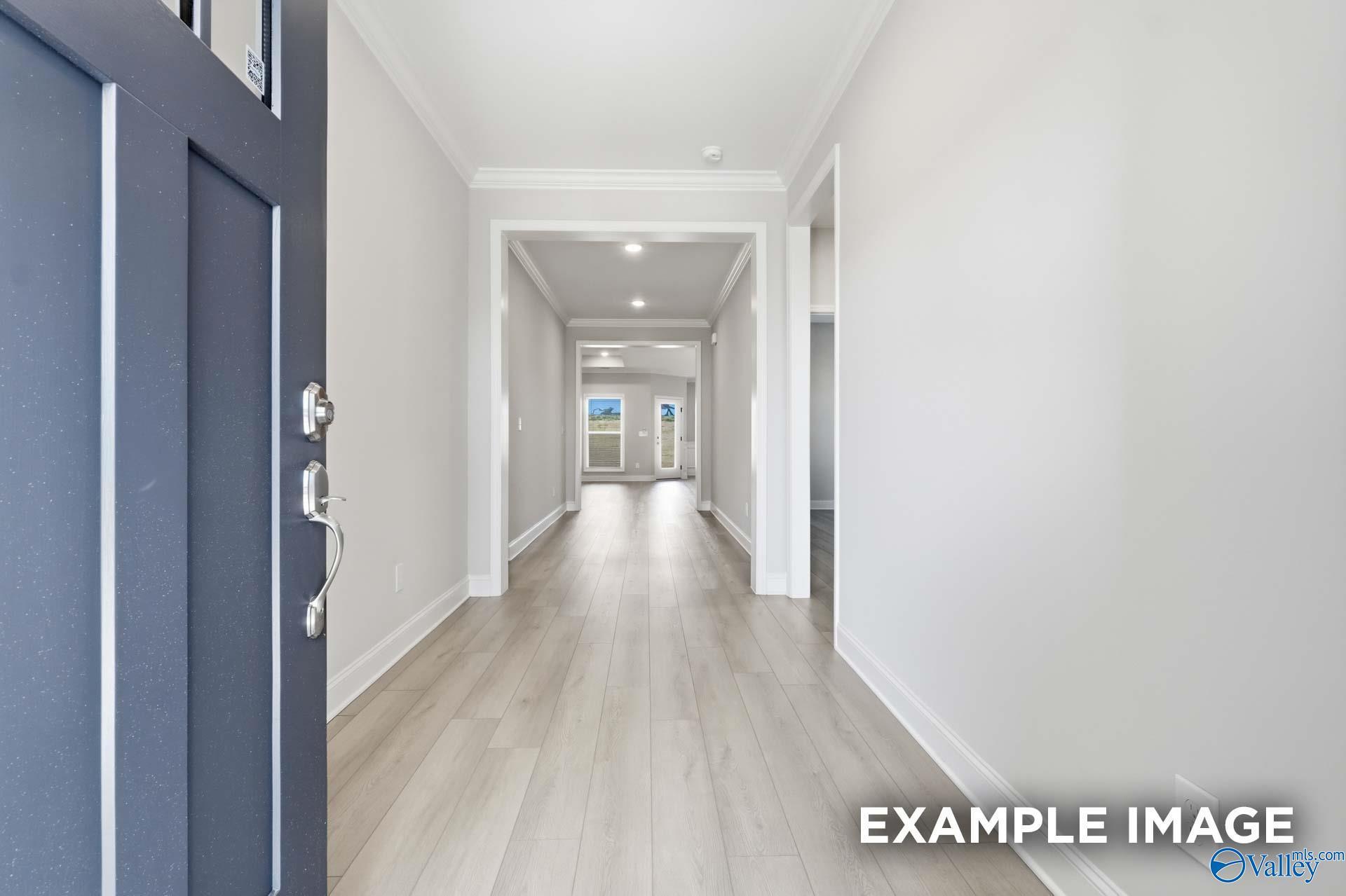 Inviting foyer hallway with navy blue door, light hardwood floors, and white trim in Davidson Homes The Harrison C, Madison AL