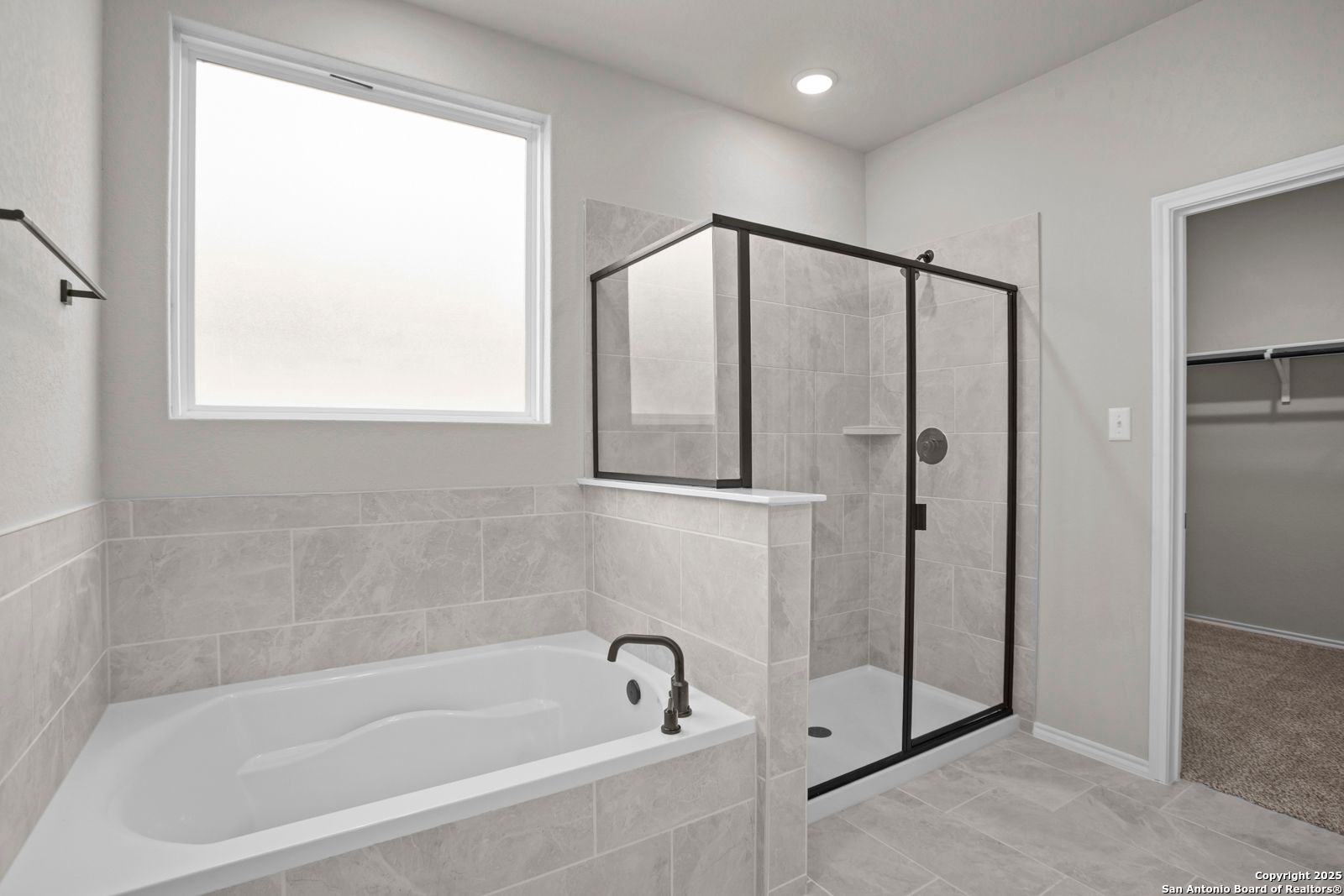 Luxurious master bathroom with glass shower enclosure, soaking tub, and tiled walls in Davidson Homes The Sequoia A, Converse, Texas
