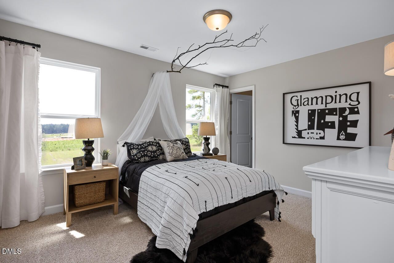 Glam camping themed bedroom with canopy bed, striped duvet, lamps, and field view in The Hickory II C, Zebulon NC