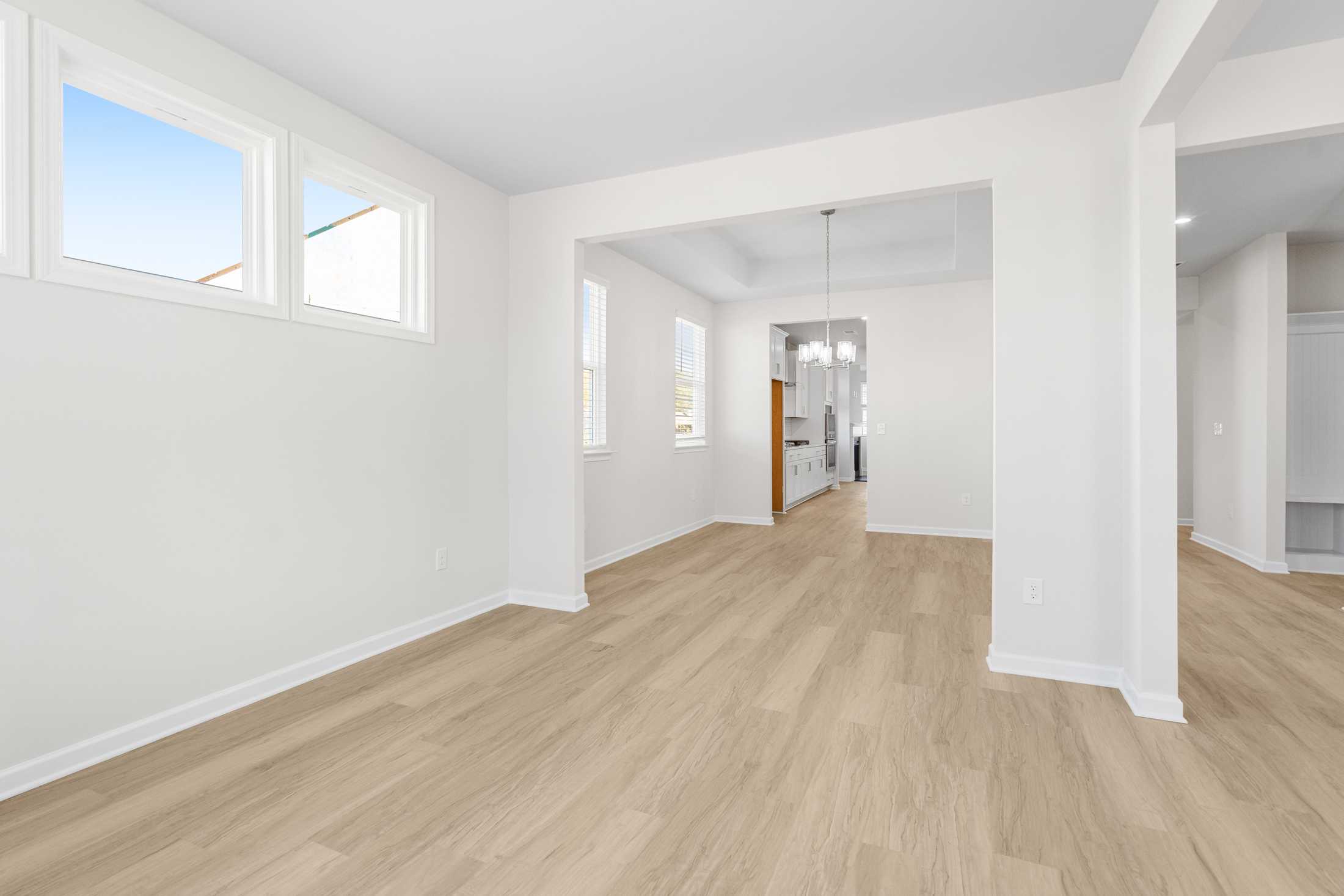 Spacious open-concept living room in The Glenwood A at Wehunt Meadows, Hoschton GA, with hardwood floors and large windows