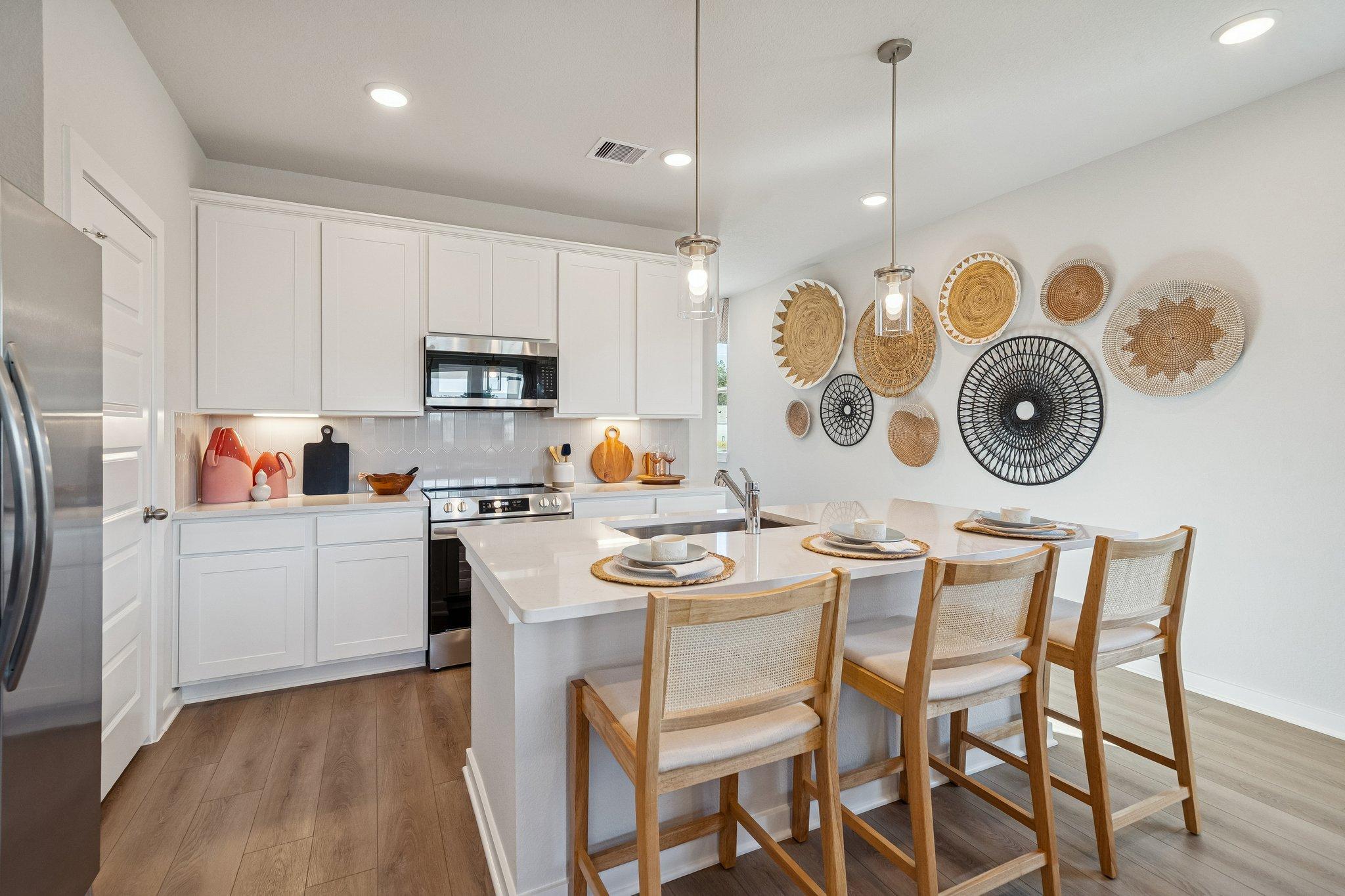 Spacious modern kitchen at Spring Branch Crossing in Conroe Texas with white cabinets island seating and woven wall decor