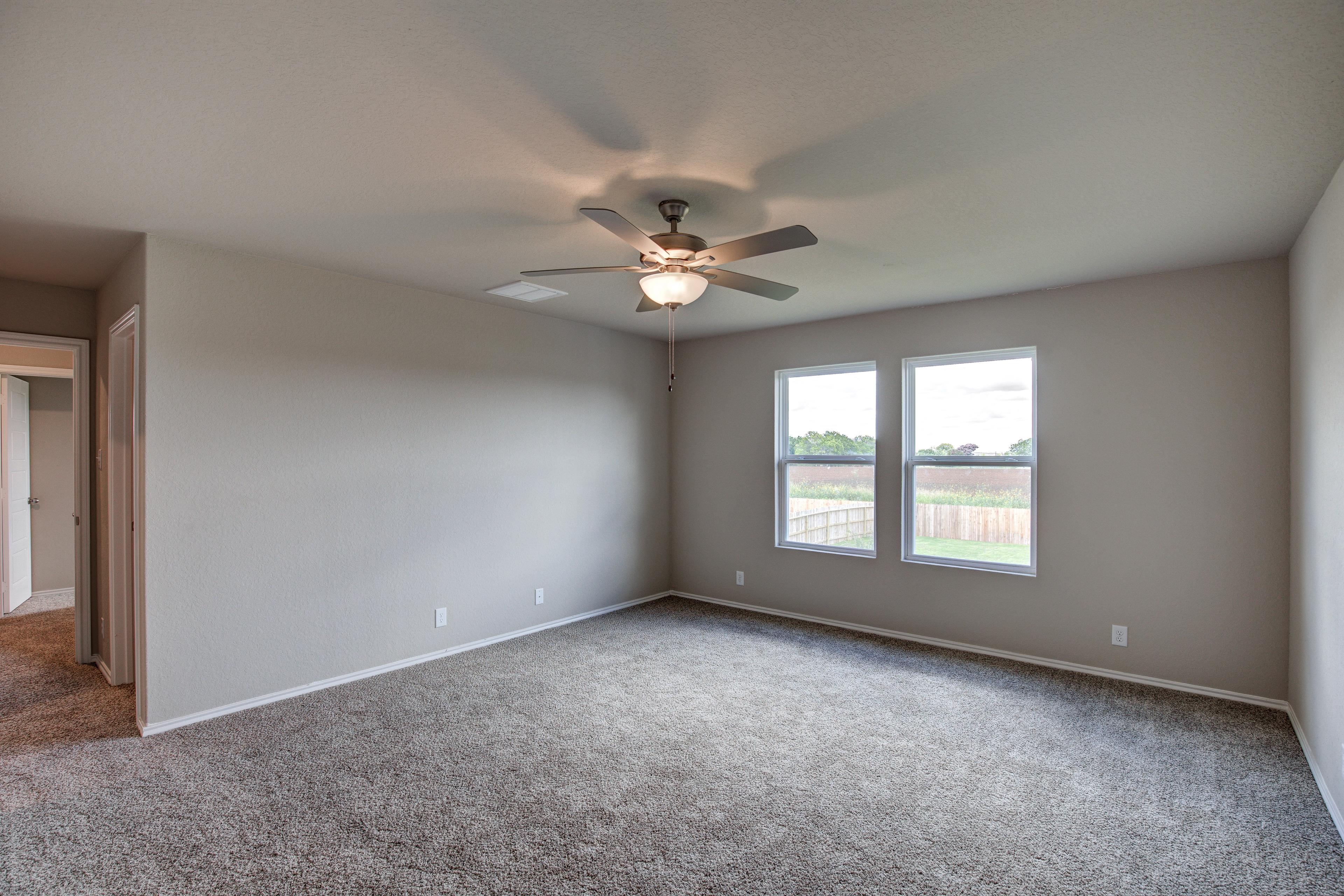Spacious master bedroom in The Murray G featuring gray walls, carpeted floor, ceiling fan, and large windows with yard view