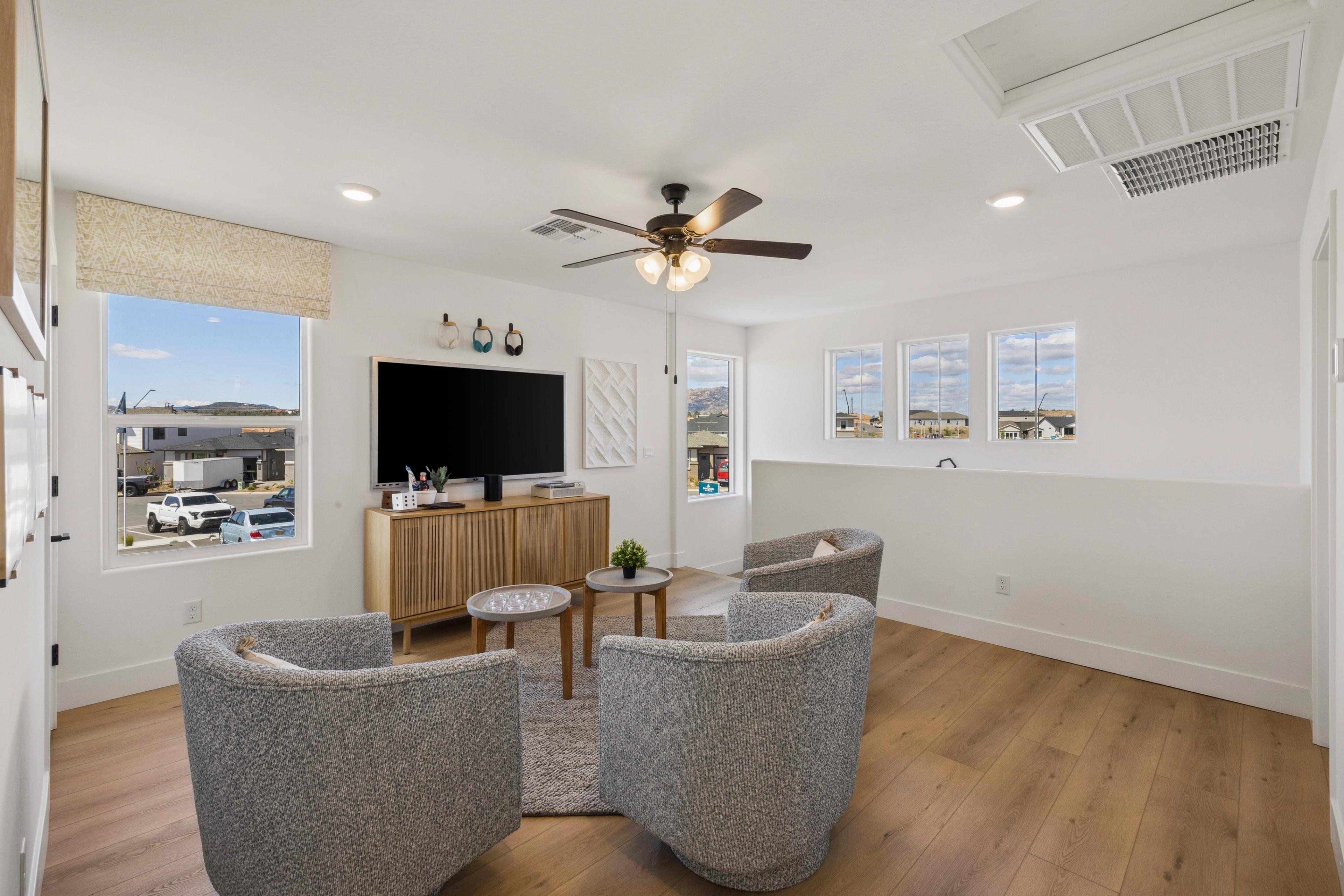 Cozy loft sitting area at South Ranch Southern Collection in Prescott AZ featuring gray swivel chairs, wood floors, TV, and mountain view windows