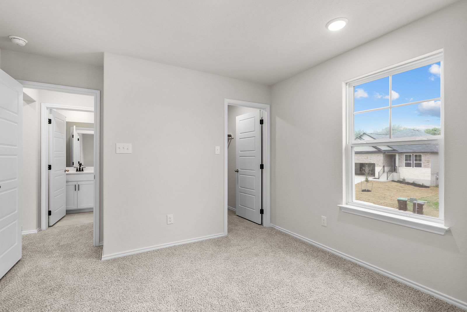 Spacious bedroom featuring plush carpet, large windows, and private access to an en-suite bathroom in The Sequoia C design.