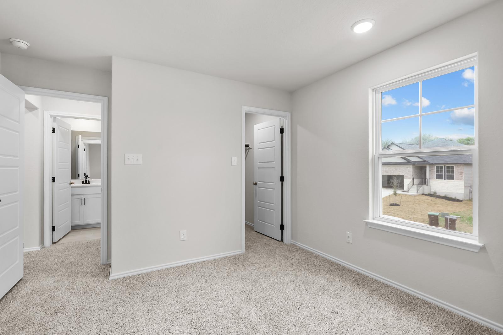 Spacious bedroom featuring plush carpet, large windows, and private access to an en-suite bathroom in The Sequoia C design.
