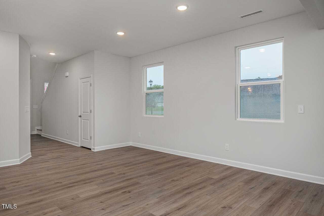 Spacious bedroom with light gray walls, hardwood floors, large windows, recessed lighting, and adjacent bath door in Davidson Homes The Adalynn B, Lillington, NC