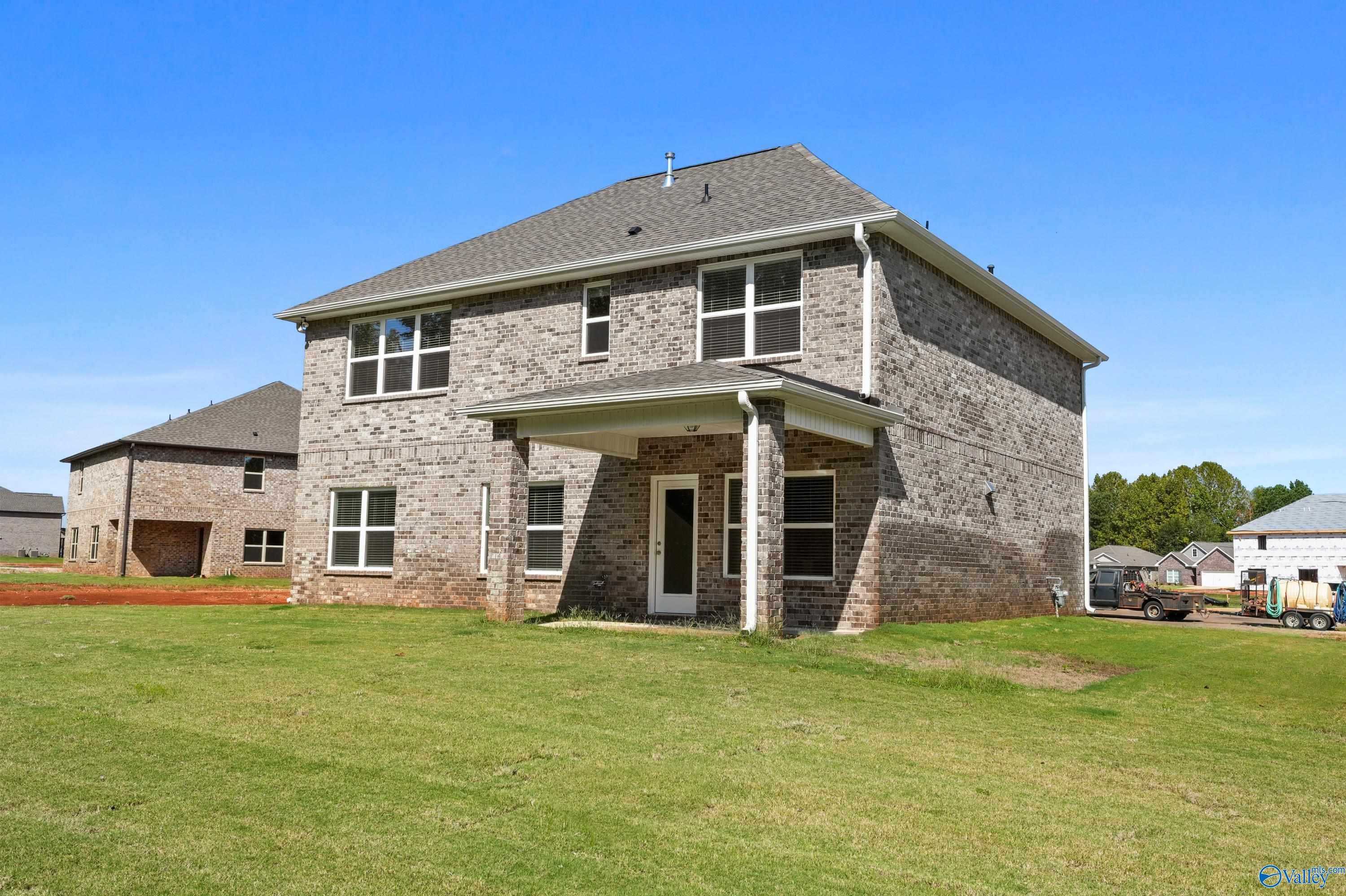 Two-story brick Shelby A home with covered porch, gabled roof, and lush green lawn in Ricketts Farm, Athens, Alabama