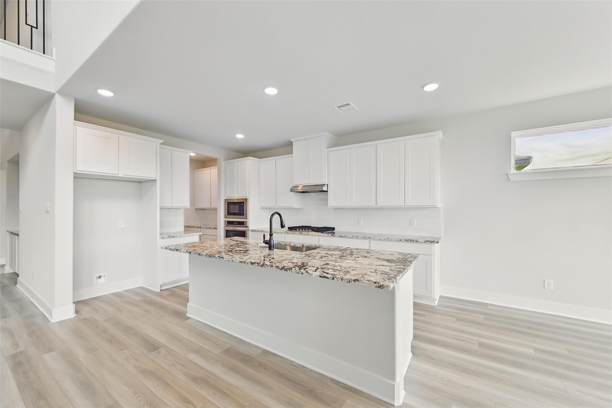 Modern white kitchen with granite island, stainless appliances, open layout in Davidson Homes The Victoria C, Lago Mar, Texas City