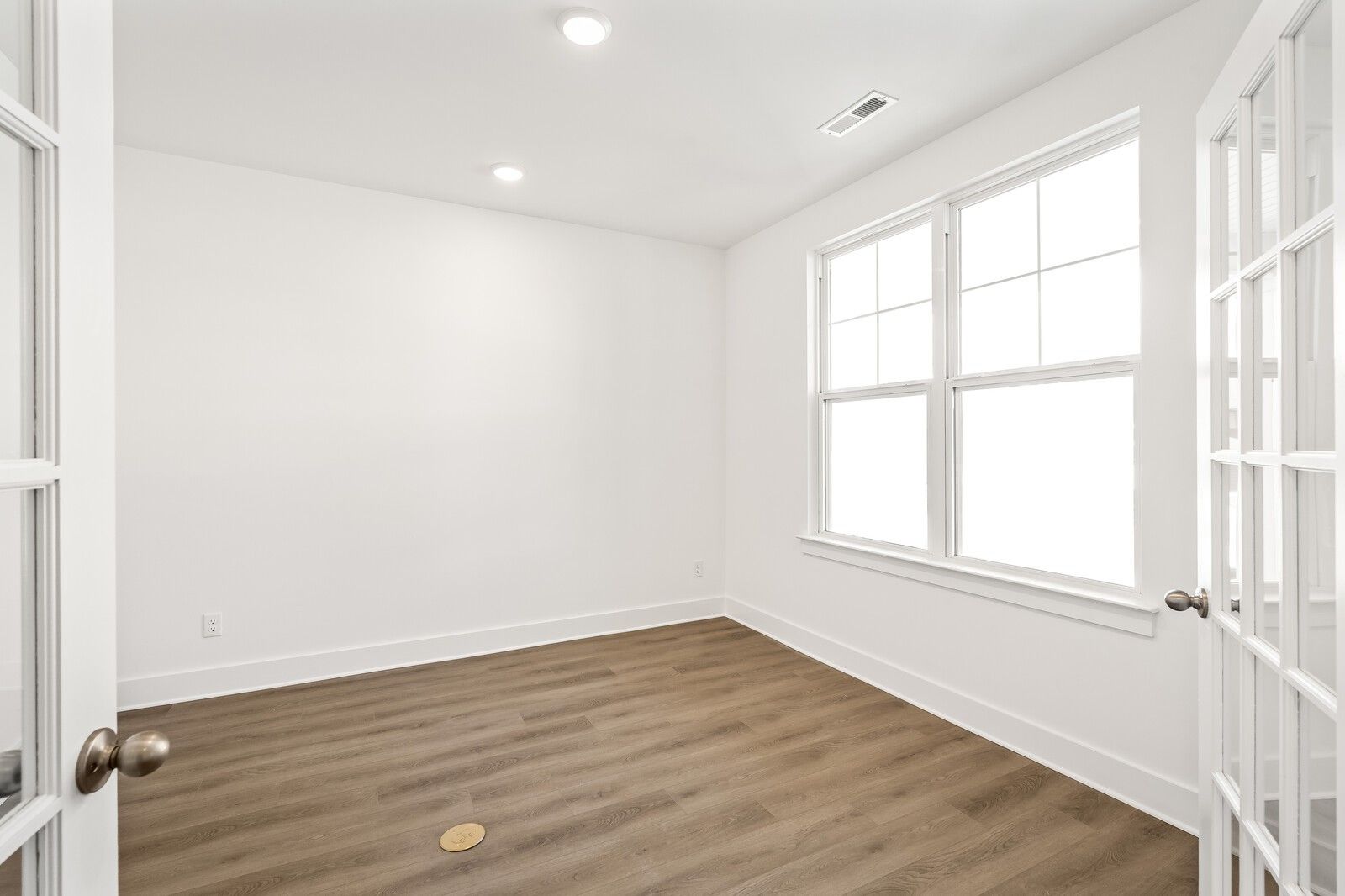 Bright empty bedroom with white walls, double doors, large windows, hardwood floors in Davidson Homes The Ash A, Gallatin, TN