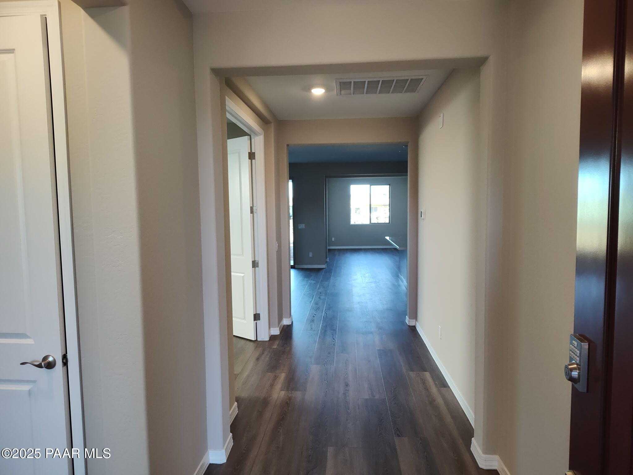 Spacious hallway with hardwood floors, arched entry, and bedroom doors in Davidson Homes The Inspiration A, Prescott Valley, Arizona