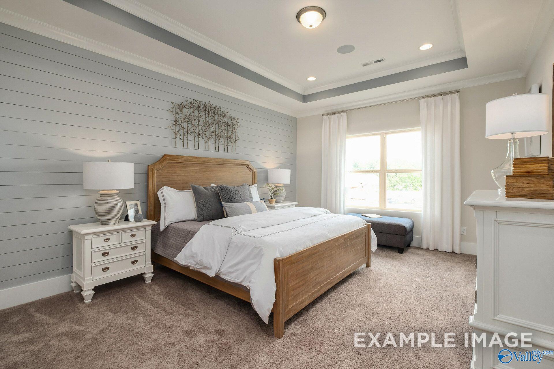 Bright master bedroom with wood bed, shiplap accent wall, and tray ceiling in Davidson Homes' The Daphne D, Toney, Alabama