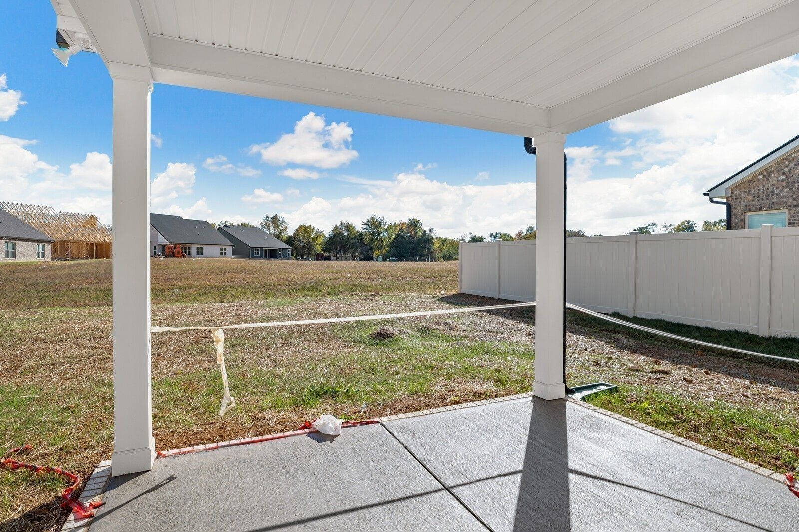 Covered back patio with white columns and concrete deck overlooking fenced backyard in Davidson Homes The Willow C, Gallatin, TN