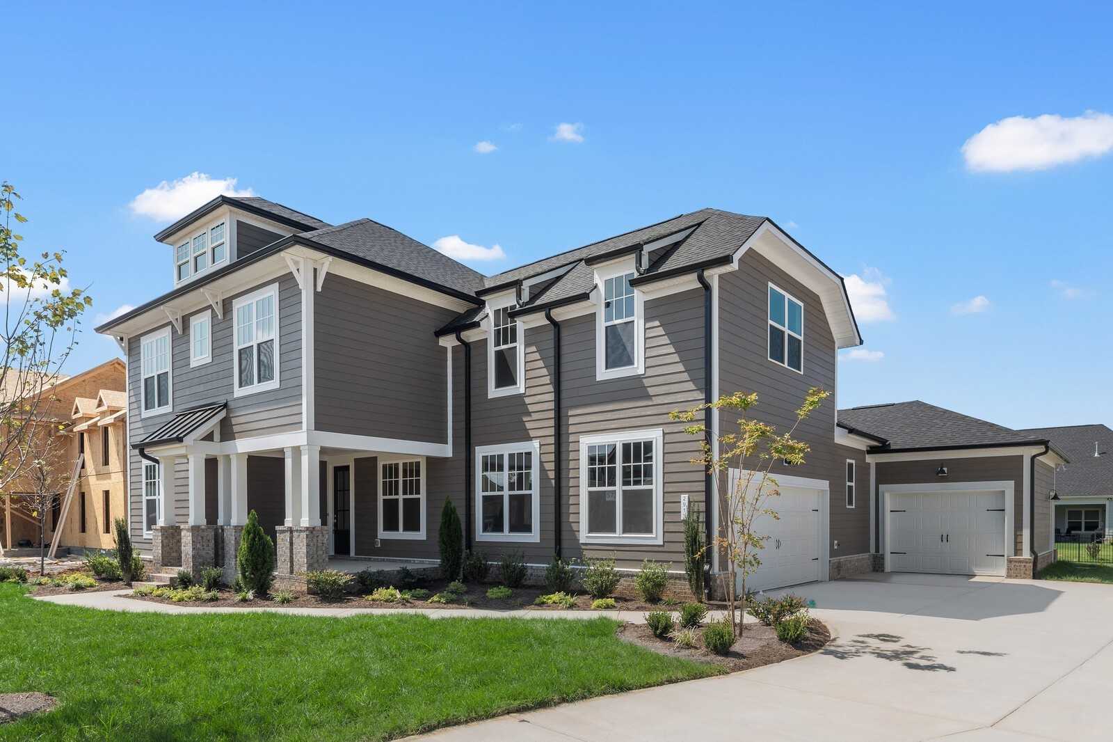 Two-story gray Hathaway home with 3-car garage, front porch, and landscaped yard by Davidson Homes in Shelton Square, Murfreesboro, Tennessee