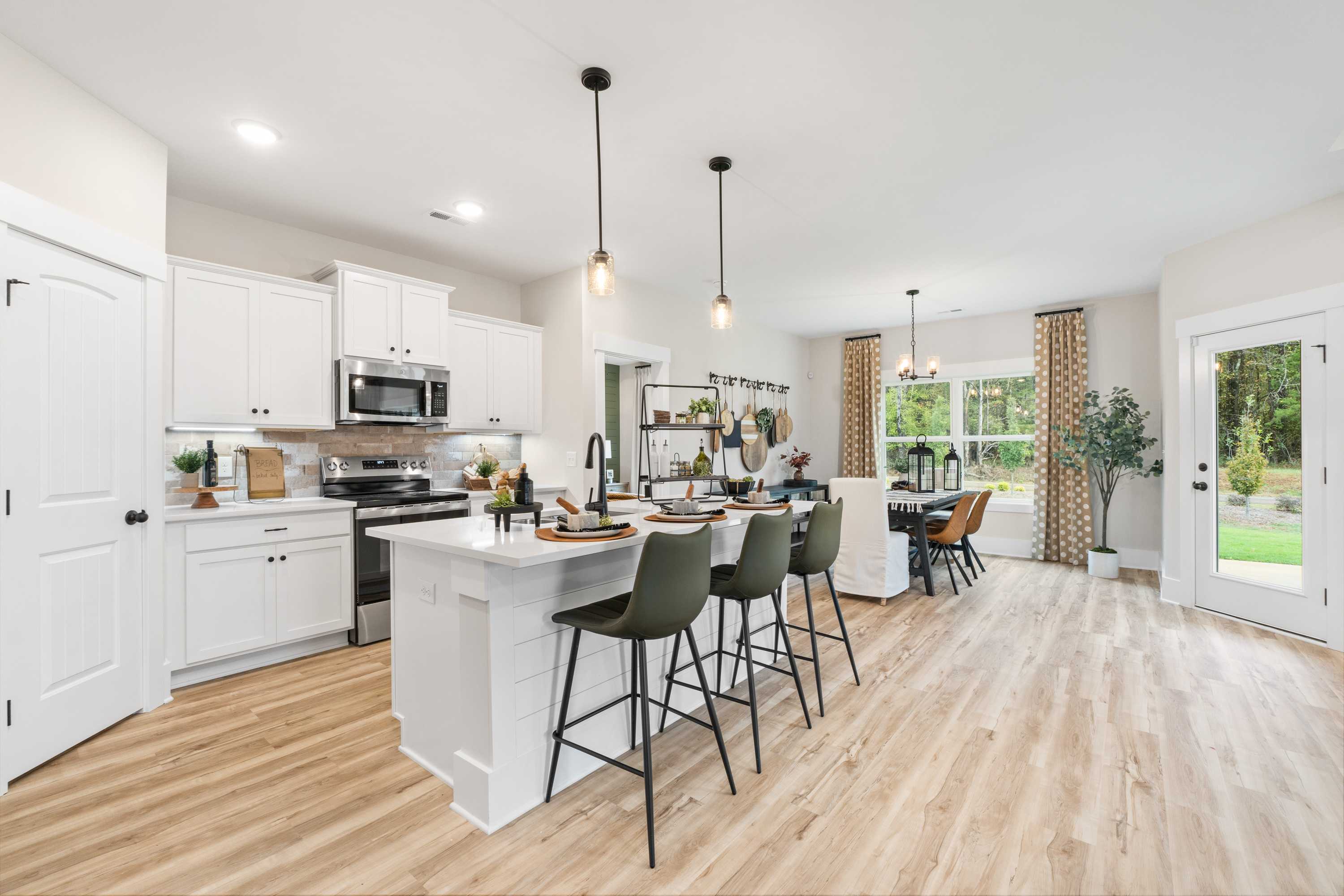 Modern kitchen at Spragins Cove in Huntsville Alabama with white cabinets, large center island, green bar stools, and hardwood floors