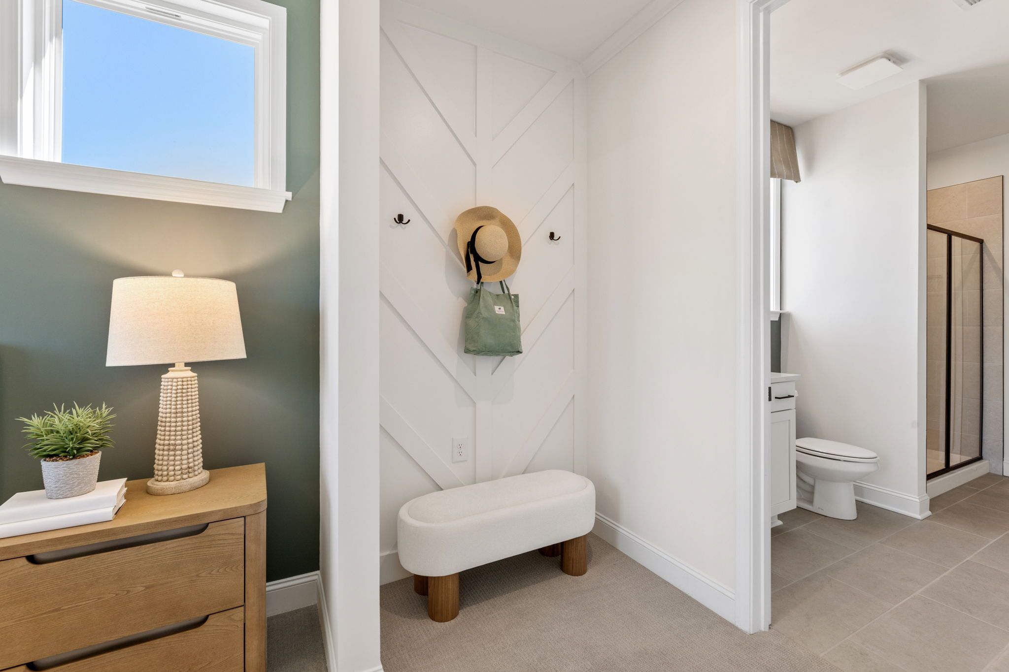 Cozy mudroom at Fern Hollow in Buford, Georgia featuring shiplap walls, woven bench, table lamp, potted plant, hat and bag hooks