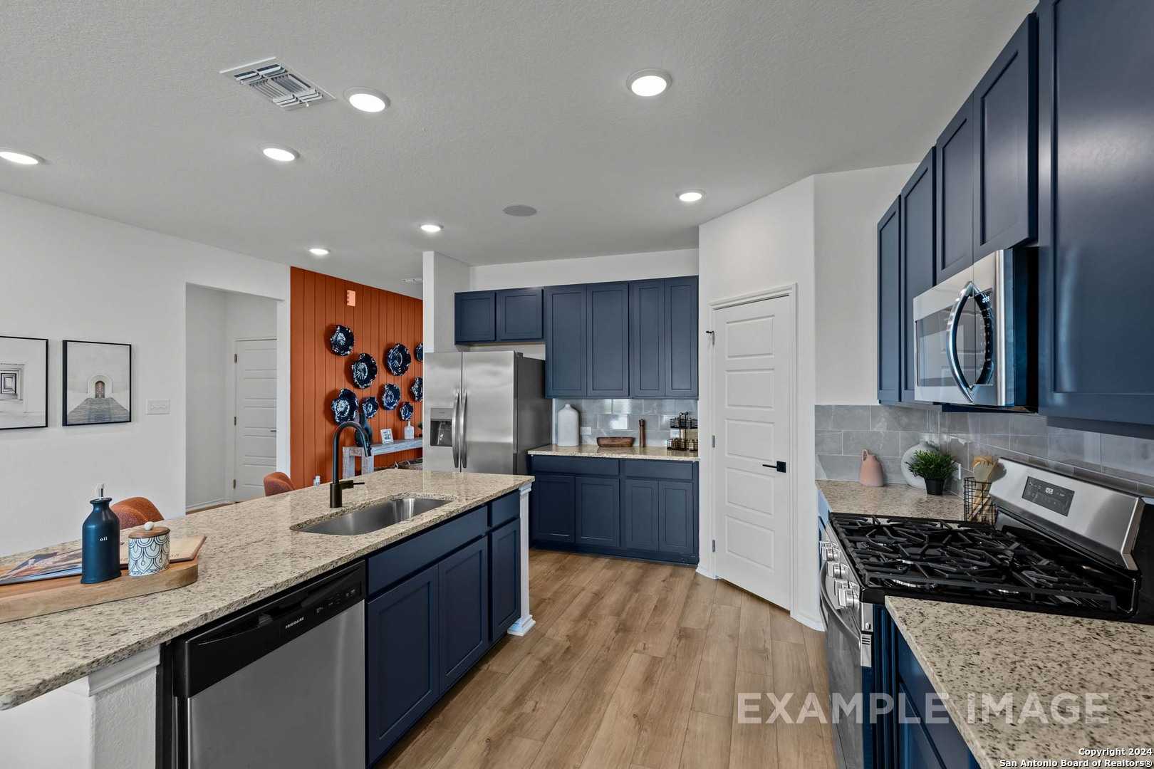 Modern navy blue kitchen with granite counters, stainless steel appliances, subway tile backsplash in Davidson Homes The Douglas G, San Antonio