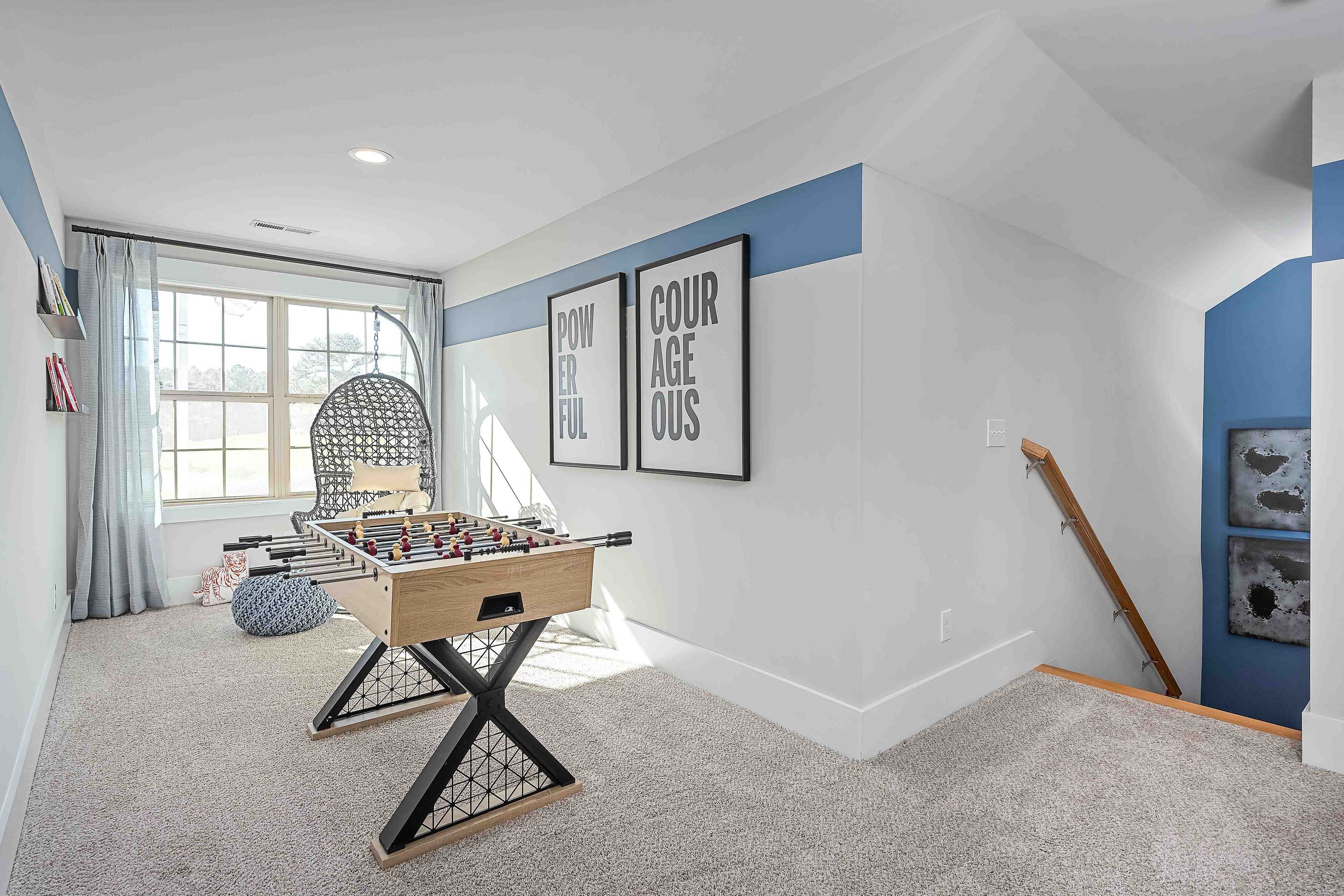 Cozy bonus room at Cain Park in Hartselle Alabama with foosball table, blue accent walls, and motivational posters