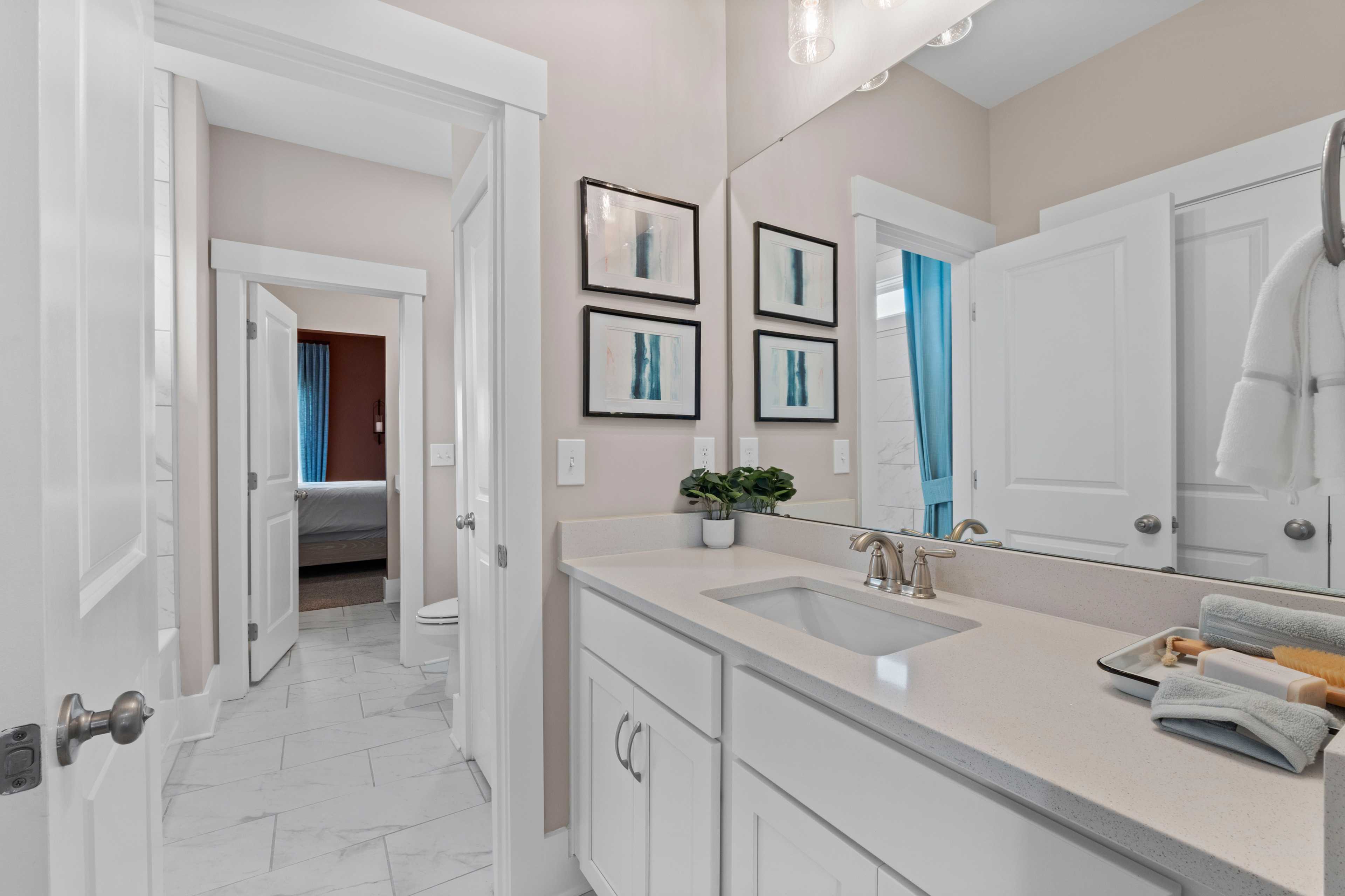 Spacious modern bathroom in Creekside Harvest Alabama featuring white shaker cabinets, quartz vanity, and abstract art