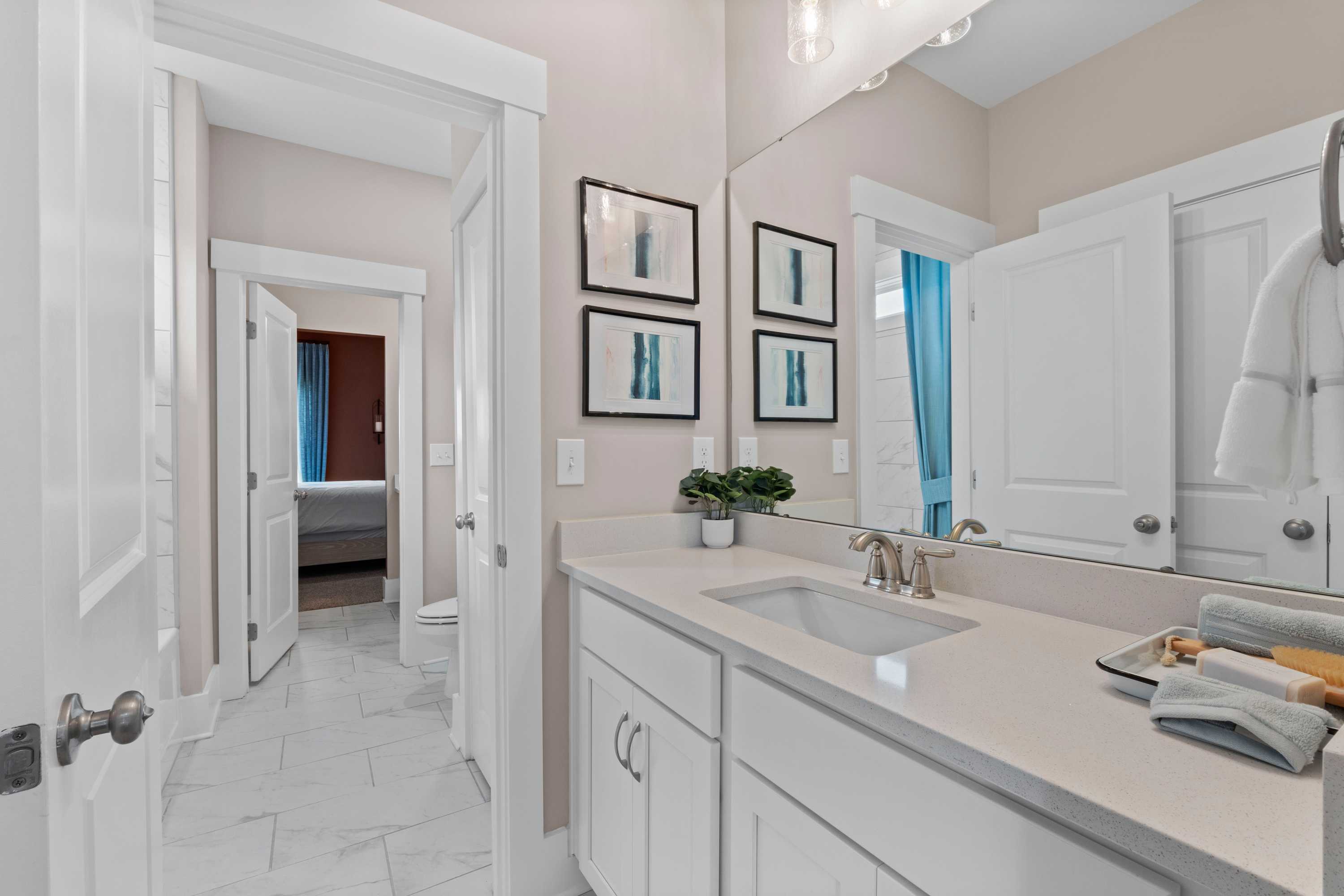 Spacious modern bathroom in Creekside Harvest Alabama featuring white shaker cabinets, quartz vanity, and abstract art