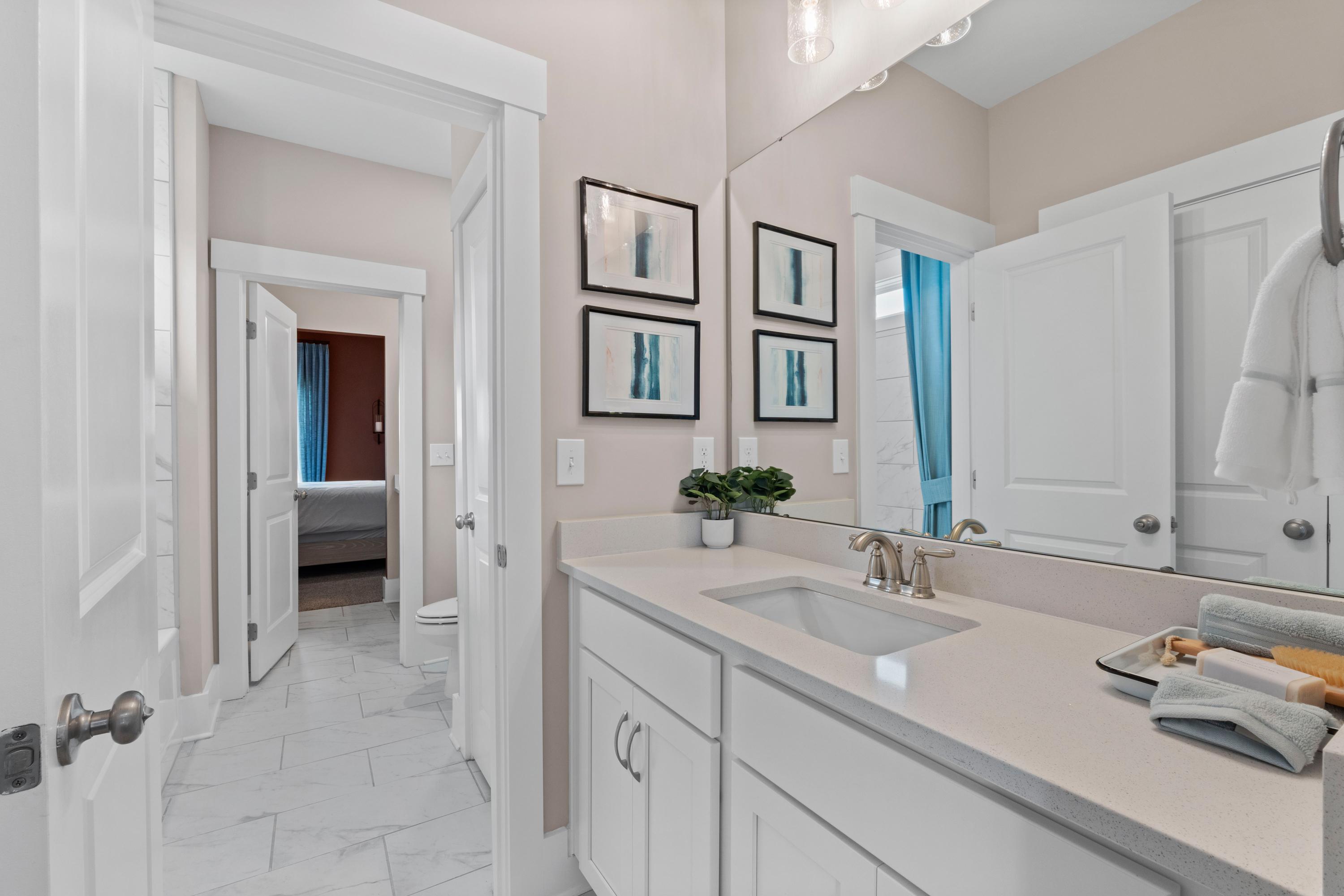 Spacious modern bathroom in Creekside Harvest Alabama featuring white shaker cabinets, quartz vanity, and abstract art