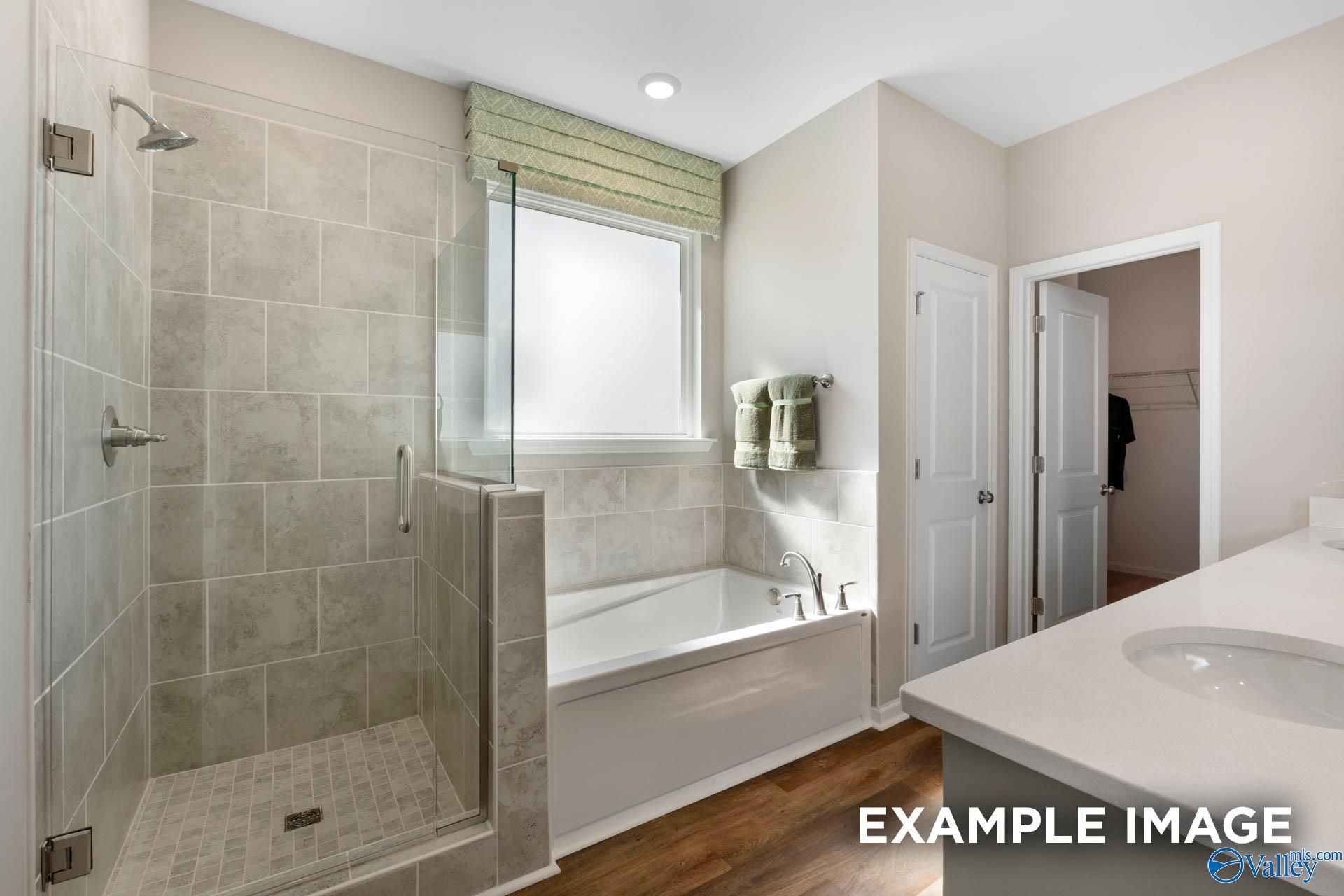Luxurious master bathroom with tiled walk-in shower, freestanding tub, and double vanity in Davidson Homes The Stella, Madison, Alabama