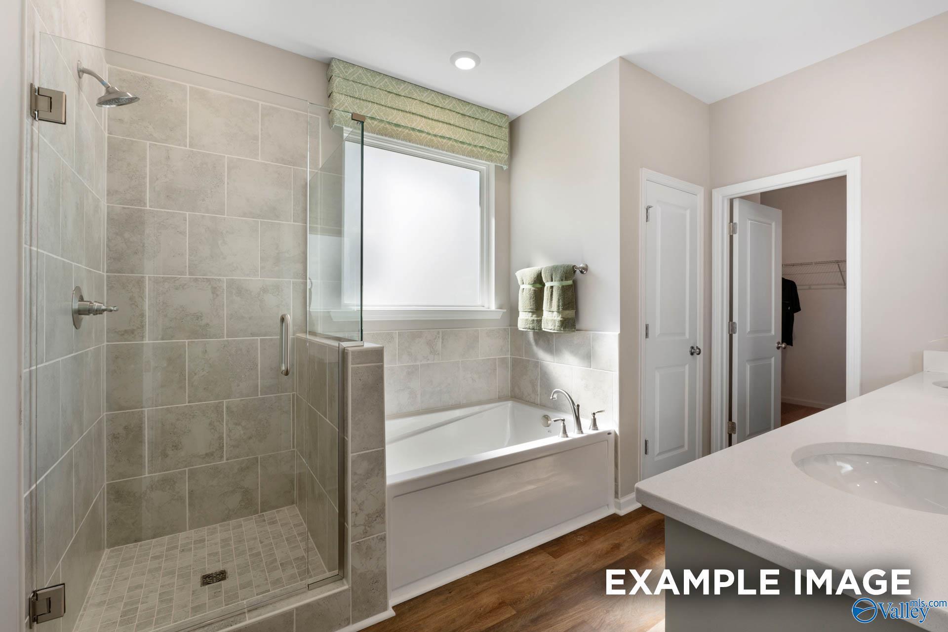 Luxurious master bathroom with tiled walk-in shower, freestanding tub, and double vanity in Davidson Homes The Stella, Madison, Alabama